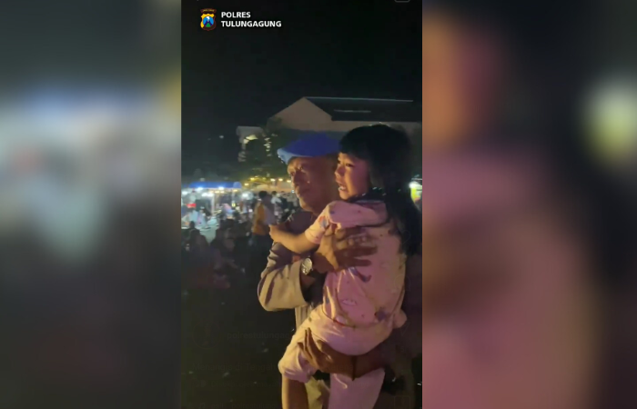 Seorang petugas sedang mengamankan anak yang terpisah dengan orang tuannya di Gor Lembu Peteng Tulungagung.
