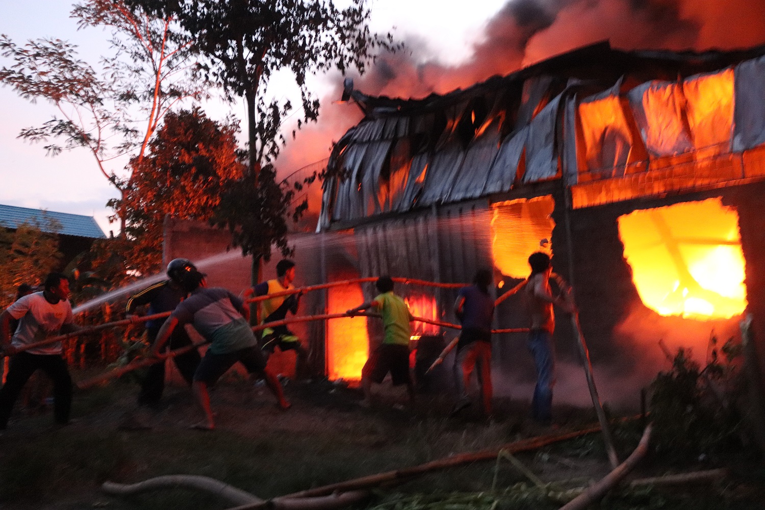 MEMBARA: Warga berusaha memadamkan api yang melalap gudang milik Ali, warga Desa Bendiljati Kulon, Kecamatan Sumbergempol. (foto: Yoga Dany Damara/Radar Tulungagung)