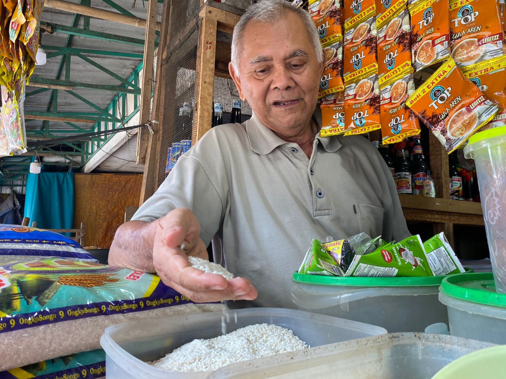 Seorang pedagang sedang menunjukkan beras yang mengalami kenaikan di Pasar Ngemplak, Tulungagung.