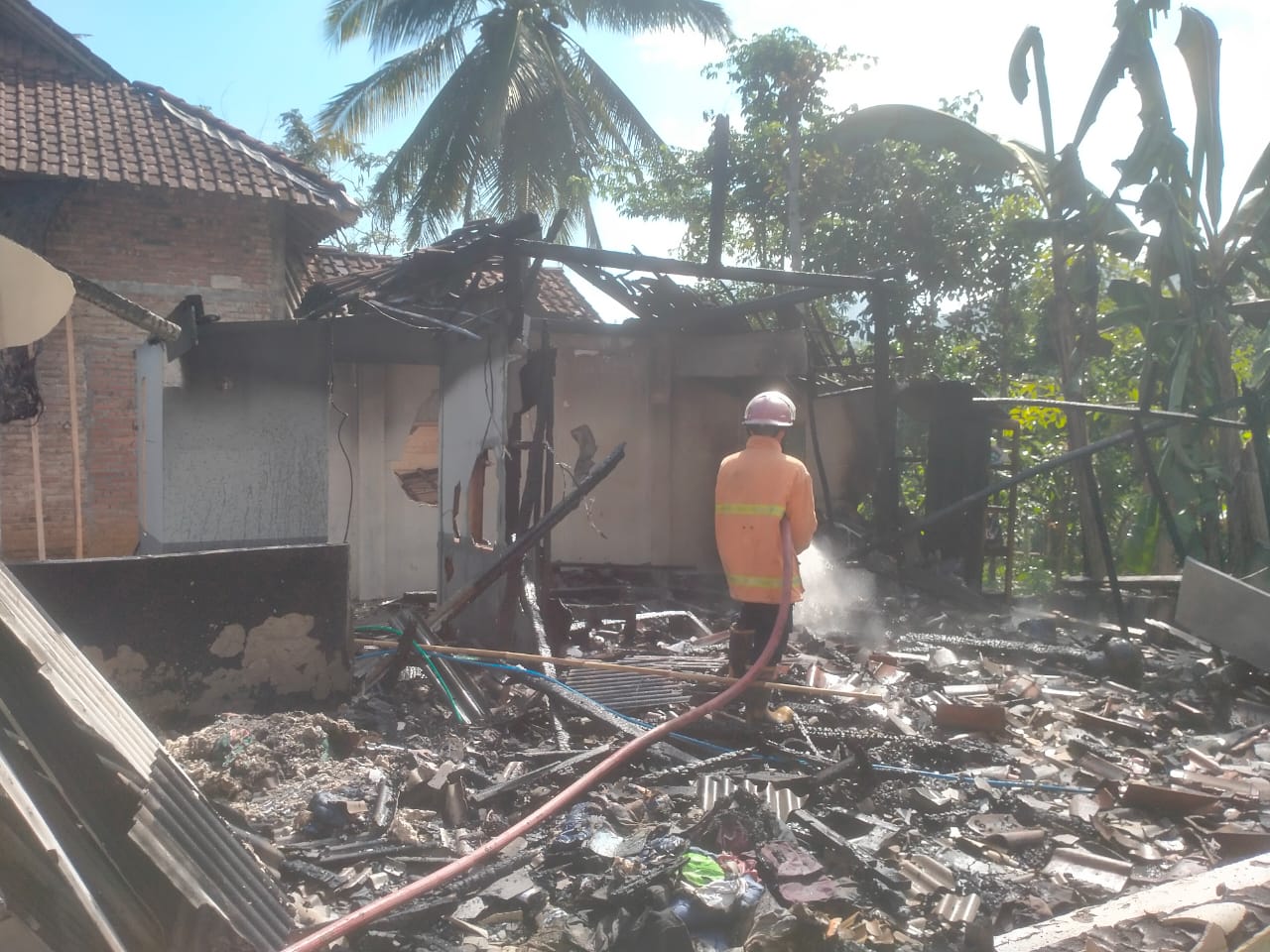 TINGGAL PUING: Pemadam kebakaran melakukan pembasahan rumah milik warga yang ludes dilalap api.