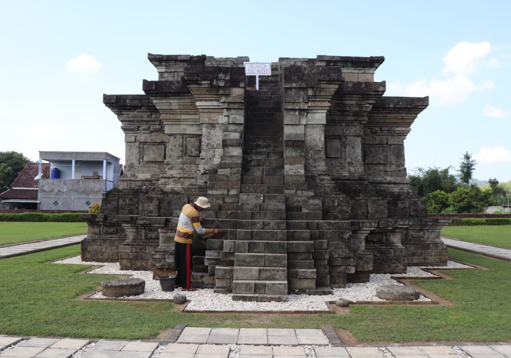 Seorang jupel sedang membersihkan Candi Sanggrahan Tulungagung.