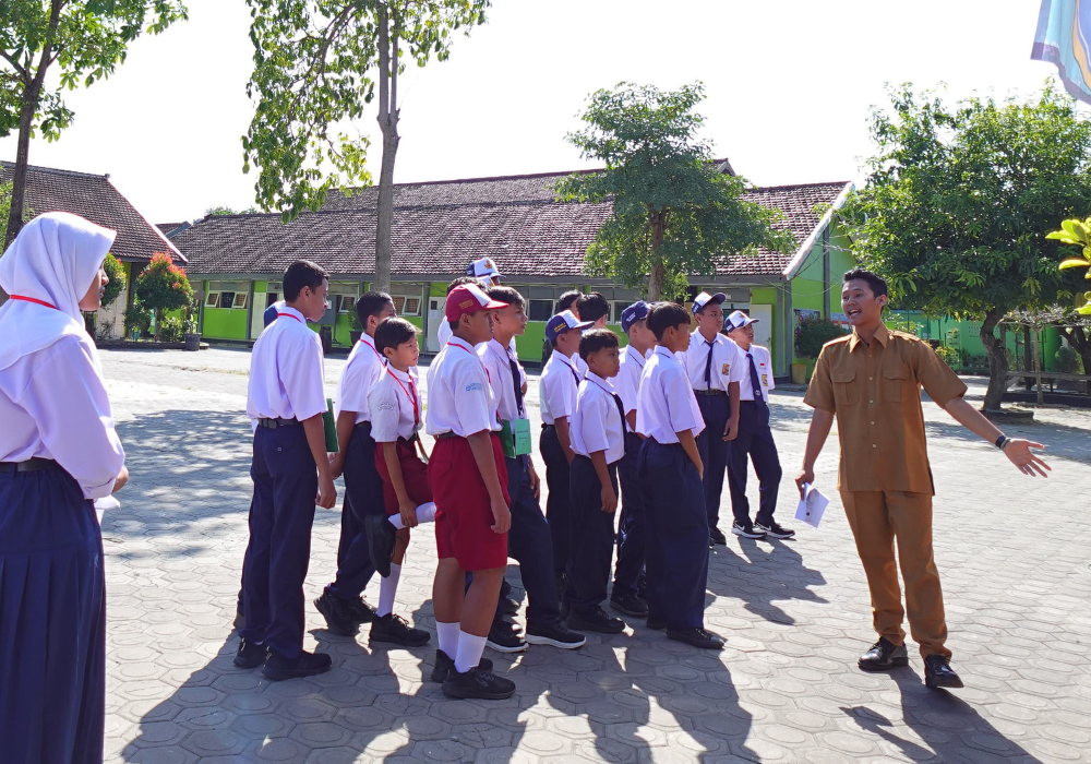 Seorang guru sedang memberikan materi MPLS kepada siswa-siswi baru di Tulungagung dengan cara yang sopan dan ramah.