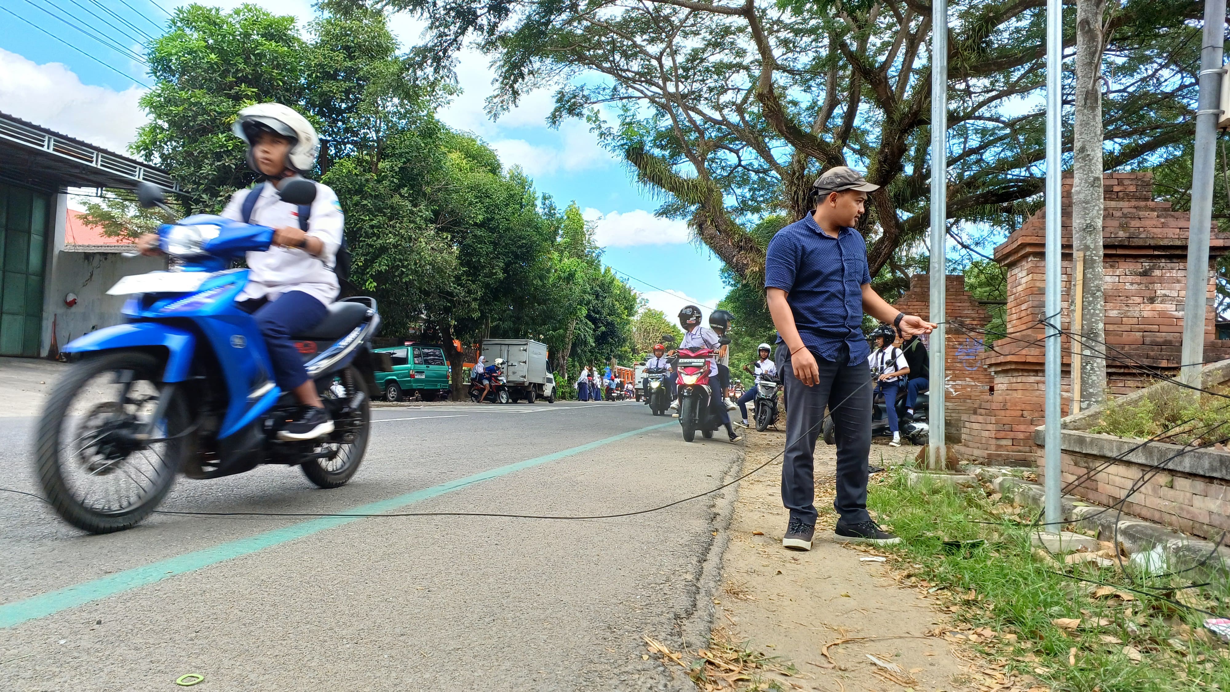 HATI-HATI: Salah seorang pengguna jalan mencoba merapikan kabel internet yang jatuh agar tidak menimbulkan korban jiwa.