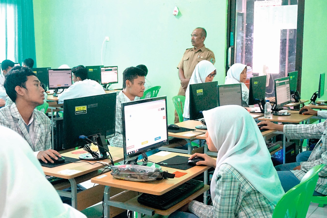 Para siswa saat mengerjakan ujian dengan diawasi oleh seorang guru.