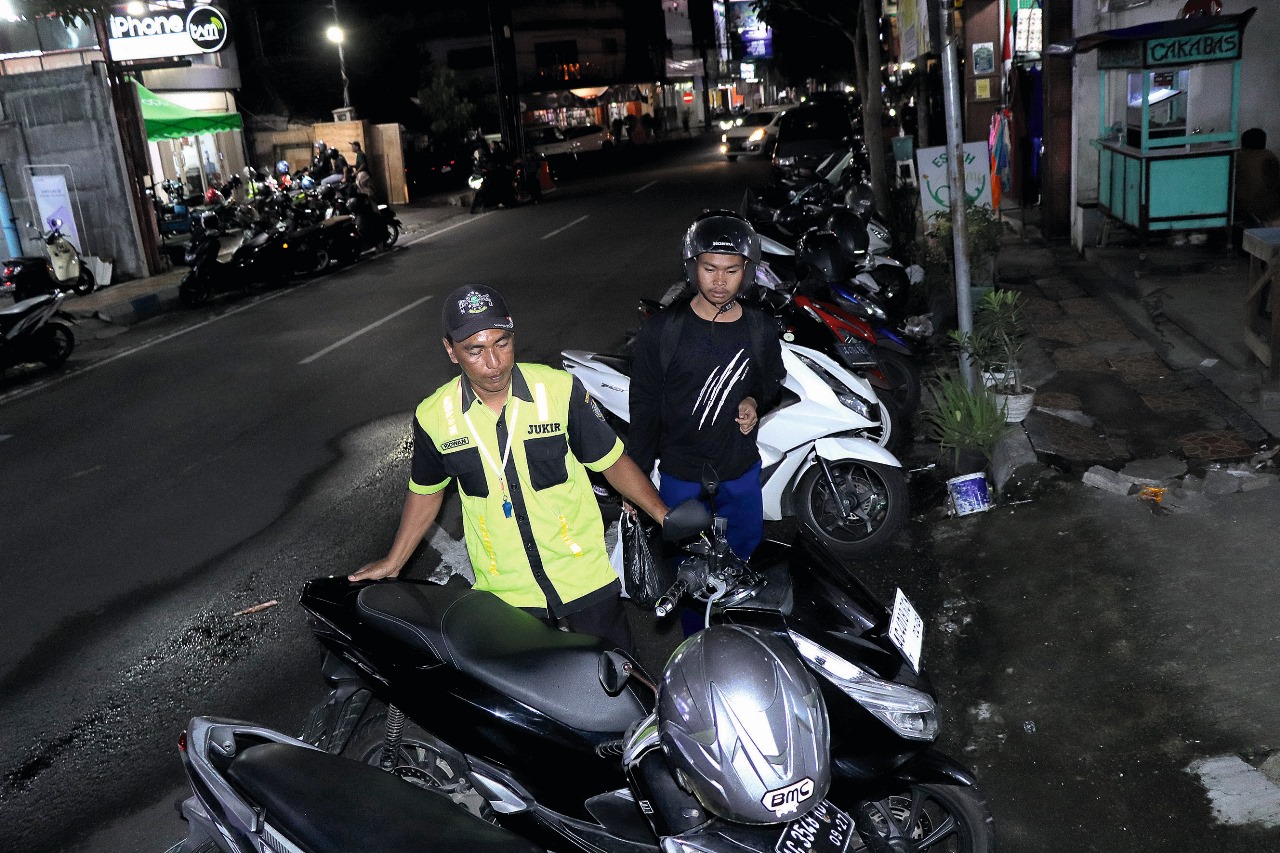 Seorang jukir sedang mengarahkan pengguna sepeda motor di Jalan Basuki Rahmat Tulungagung.