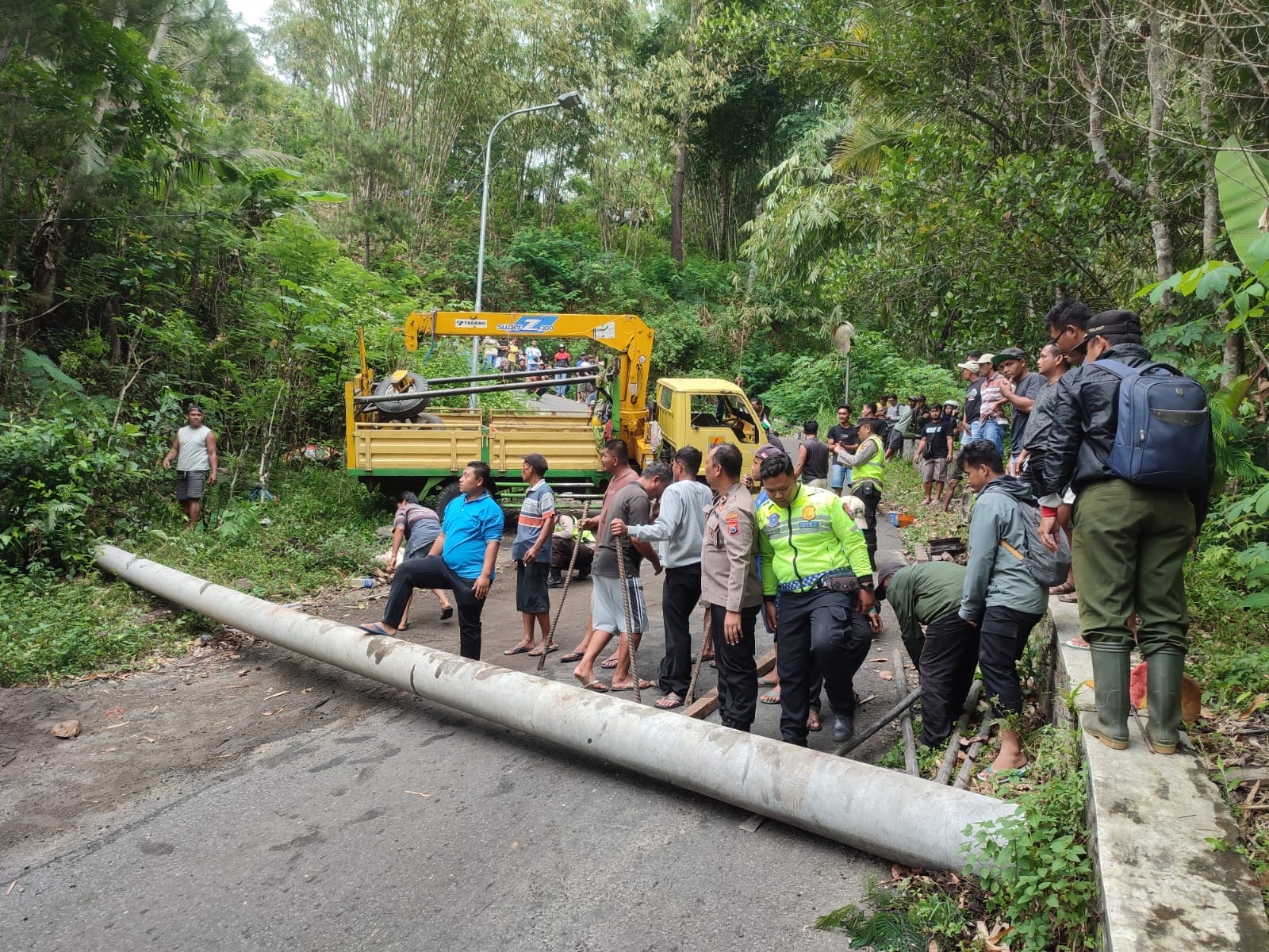 TAK ADA KORBAN JIWA: Personel Polres Trenggalek bersama warga setempat berupaya mengevakuasi truk yang laka.