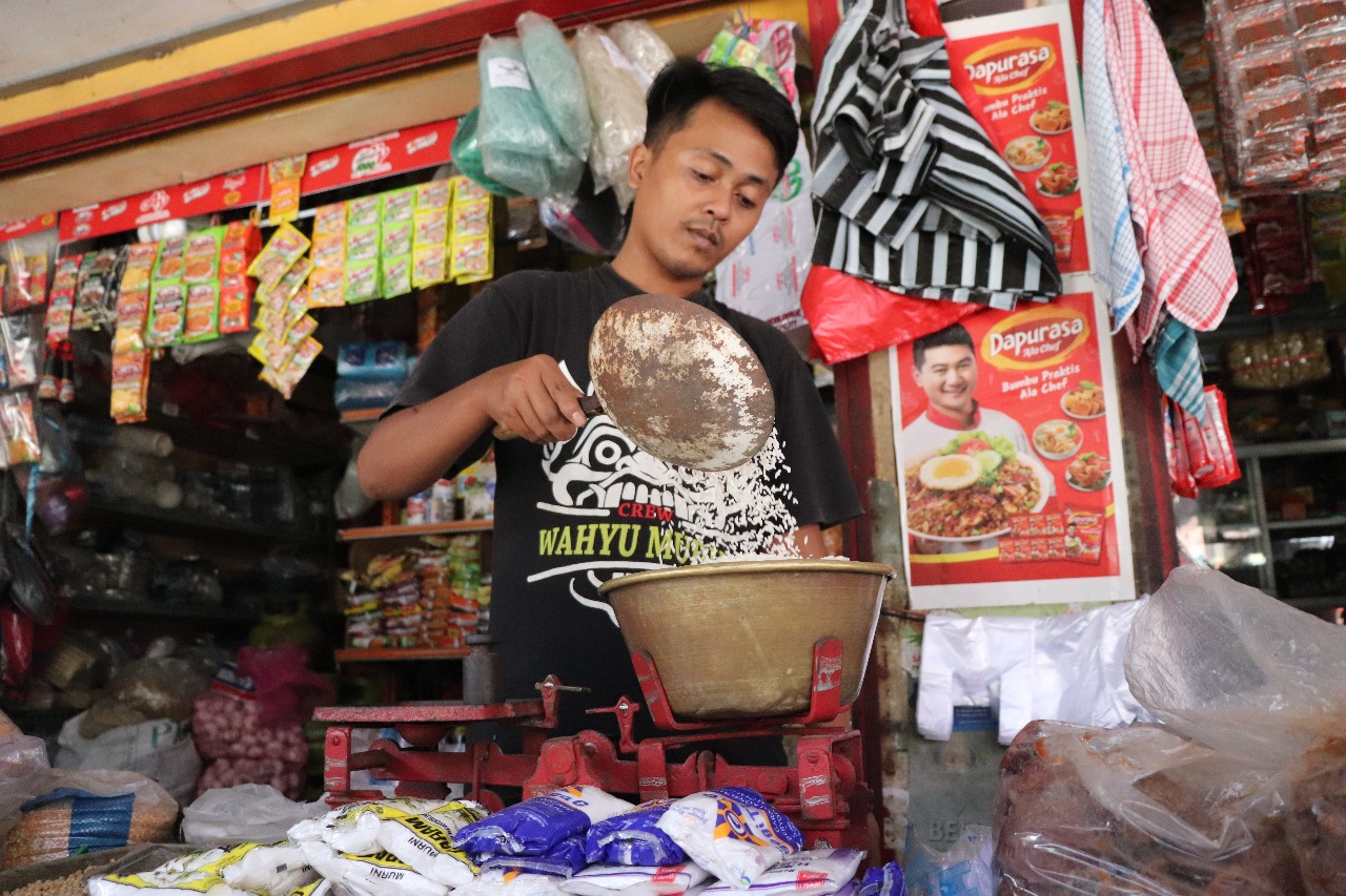 Salah satu pedagang sembako di Pasar Ngemplak sedang menimbang beras barang dagangannya, kemarin (19/12).