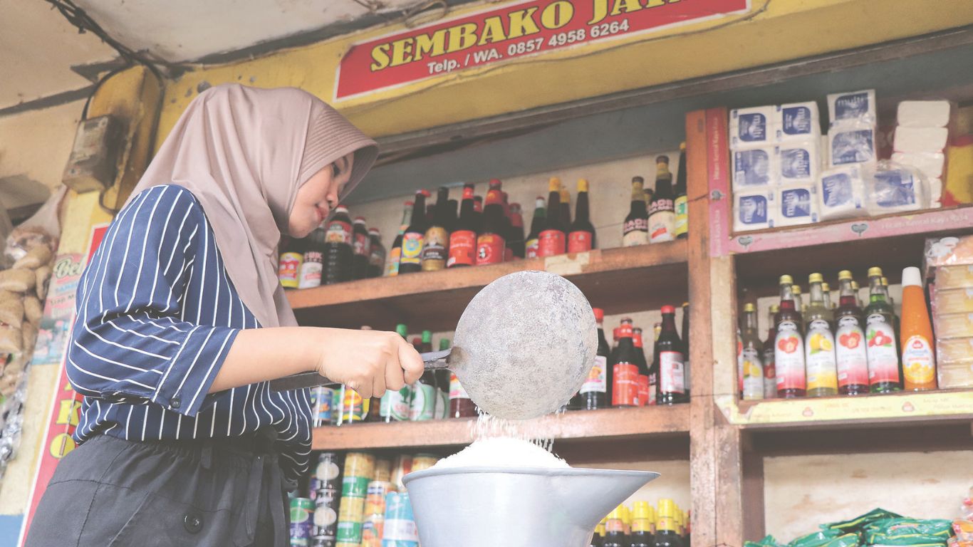 Salah satu pedagang sembako di Pasar Ngemplak sedang menimbang beras  dagangannya. Harga bapok mengalami kenaikan menjelang perayaan Nataru.(YOGA DANY DAMARA)