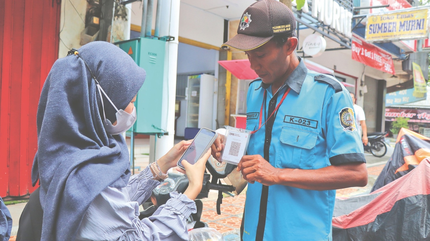 Pengendara motor saat membayar retribusi parkir menggunakan fitur QRIS di Jalan Basuki Rahmat Tulungagung.(YOGA DANY DAMARA/RADAR TULUNGAGUNG)