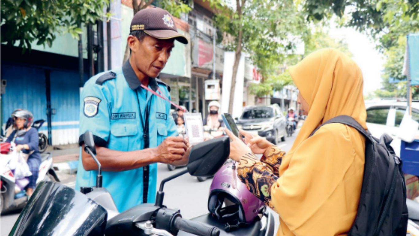 Petugas parkir melayani pengendara motor yang membayar parkir melalui transaksi dengan QRIS di Jalan Basuki Rahmat, Kelurahan Kampungdalem, Kecamatan Tulungagung.(YOGA DANY DAMARA)