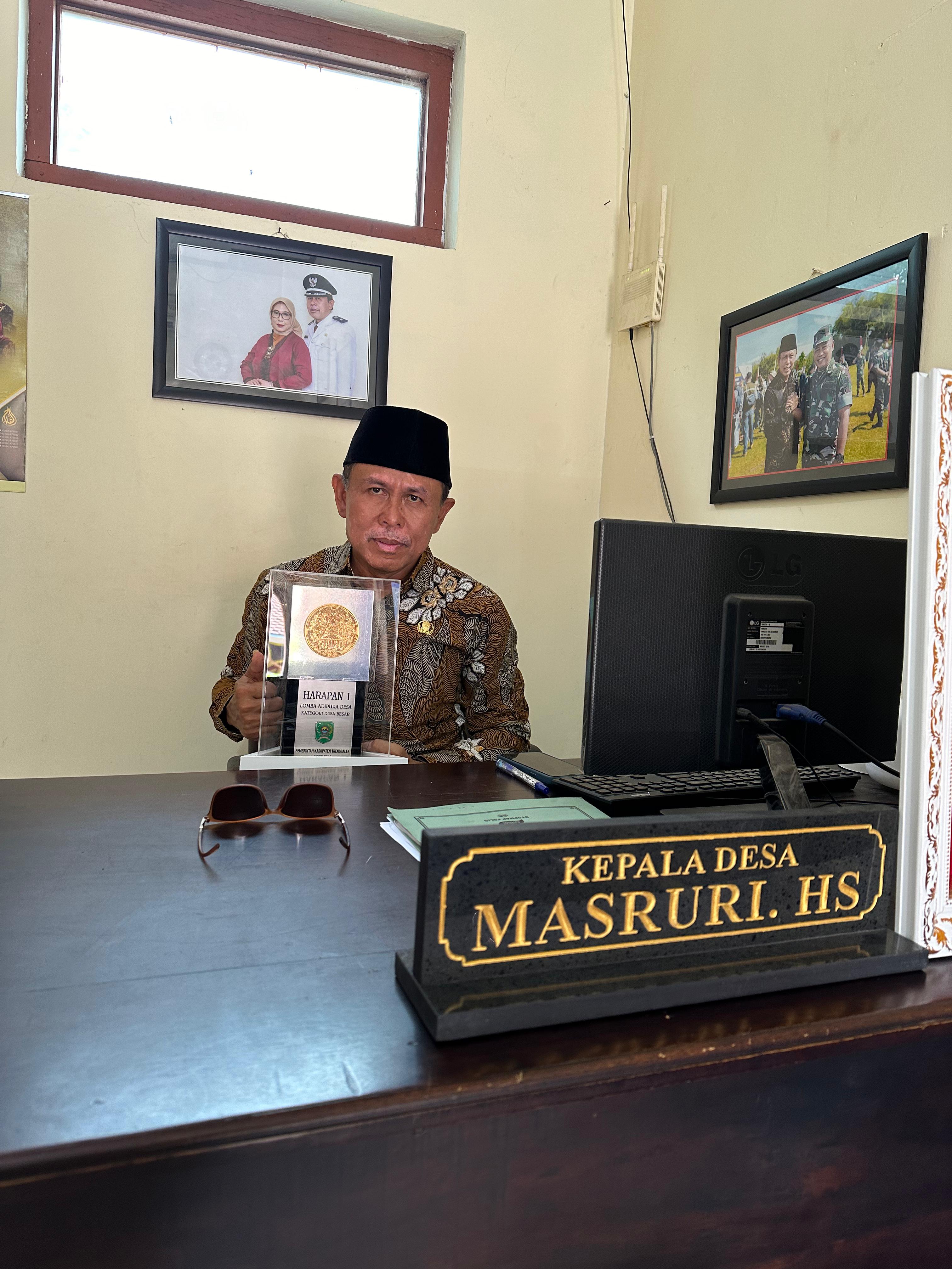 MEMBANGGAKAN: Kepala Desa (Kades) Kamulan, Masruri. HS., menunjukkan piala adipura yang diraih desanya.