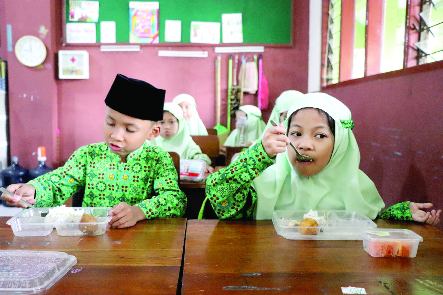  Seorang siswi SDI Al Azhaar menikmati menu makan bergizi gratis (MBG).(YOGA DANY DAMARA/RADAR TULUNGAGUNG)