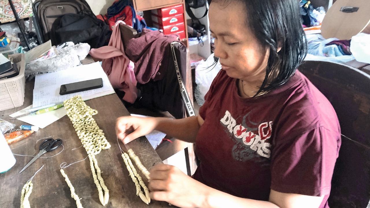 Nanik Sriwiyani saat sedang meronce melati untuk keperluan upacara adat.