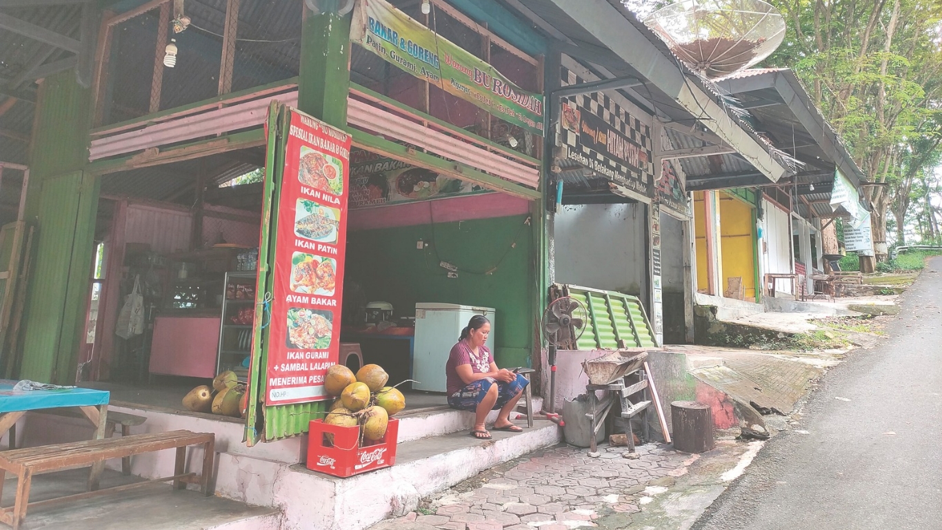 Salah satu pemilik warung di kawasan objek  wisata Waduk Wonorejo sedang menunggu wisatawan datang.