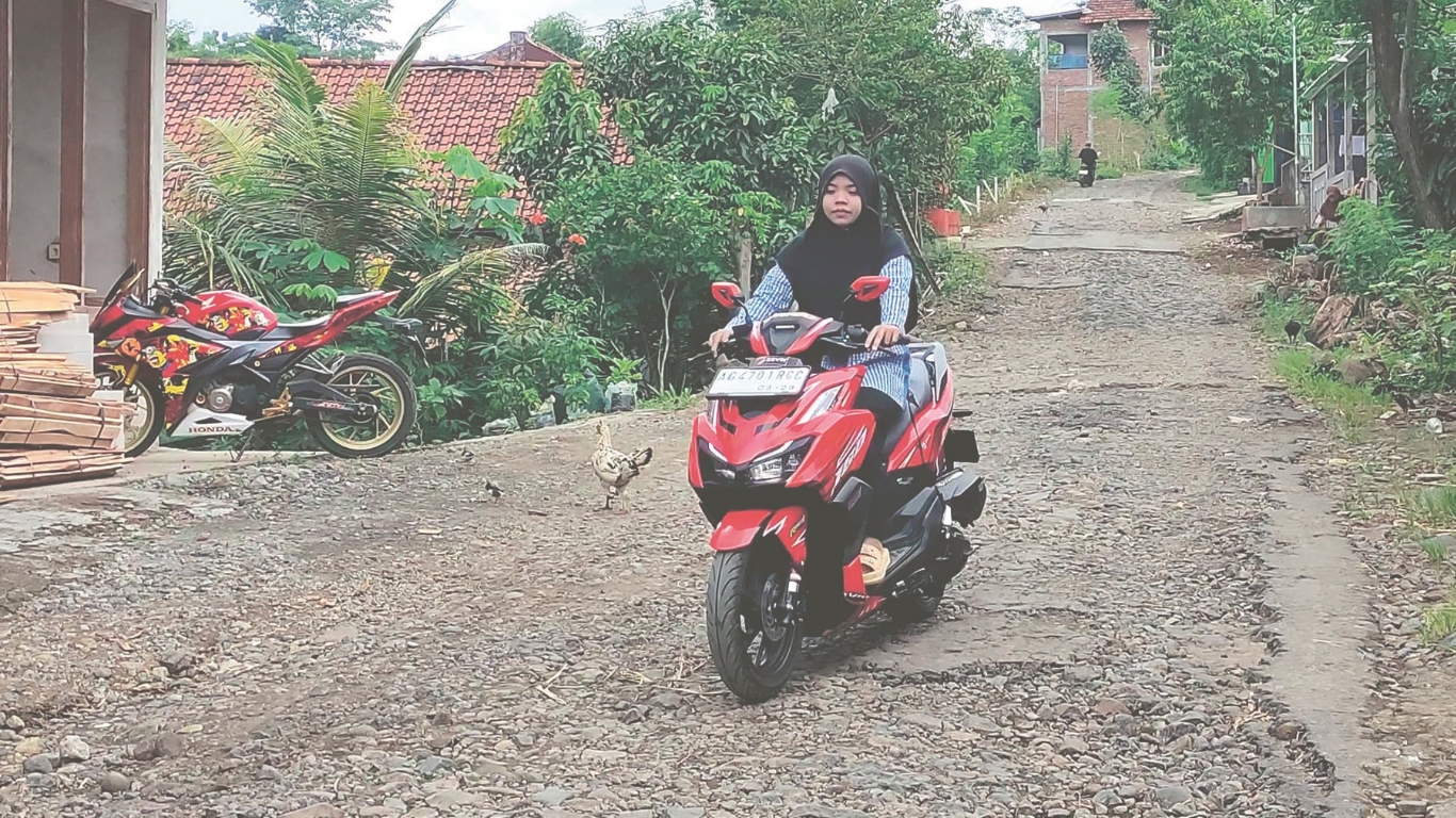 Seorang warga terlihat berhati-hati melintas di Desa Nglutung, Kecamatan Sendang, dengan kondisi jalan yang rusak berat.