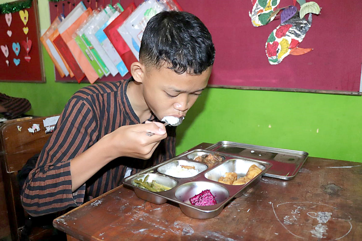Salah satu siswa sedang menikmati makanan bergizi gratis.