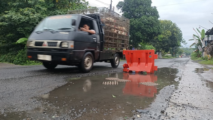 WASPADA: Pengendara menghindari lubang di jalan dengan melaju sedikit ke sisi kanan. Hujan ataupun banjir diduga ikut jadi pemicu rusaknya jalan.