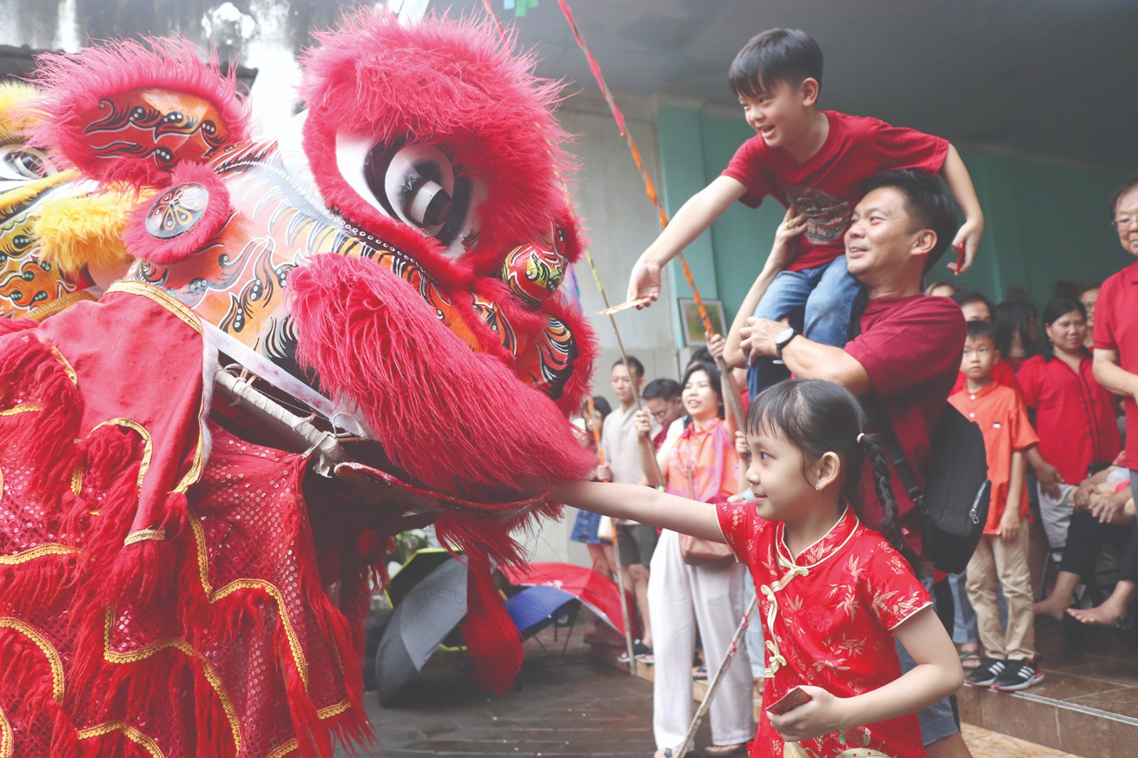 Henry Gunawan menggendong anaknya saat memberikan angpau kepada penari barongsai yang tampil menghibur di rumah keluarga besarnya, di Jalan WR Supratman, Kecamatan  Tulungagung.