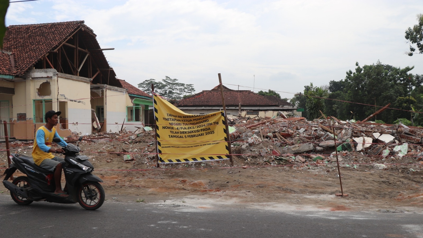 Tampak pengguna jalan melintasi puing-puing yang masih berserakan di bekas gedung Puskesmas Banjarejo, Kecamatan Rejotangan, Tulungagung.