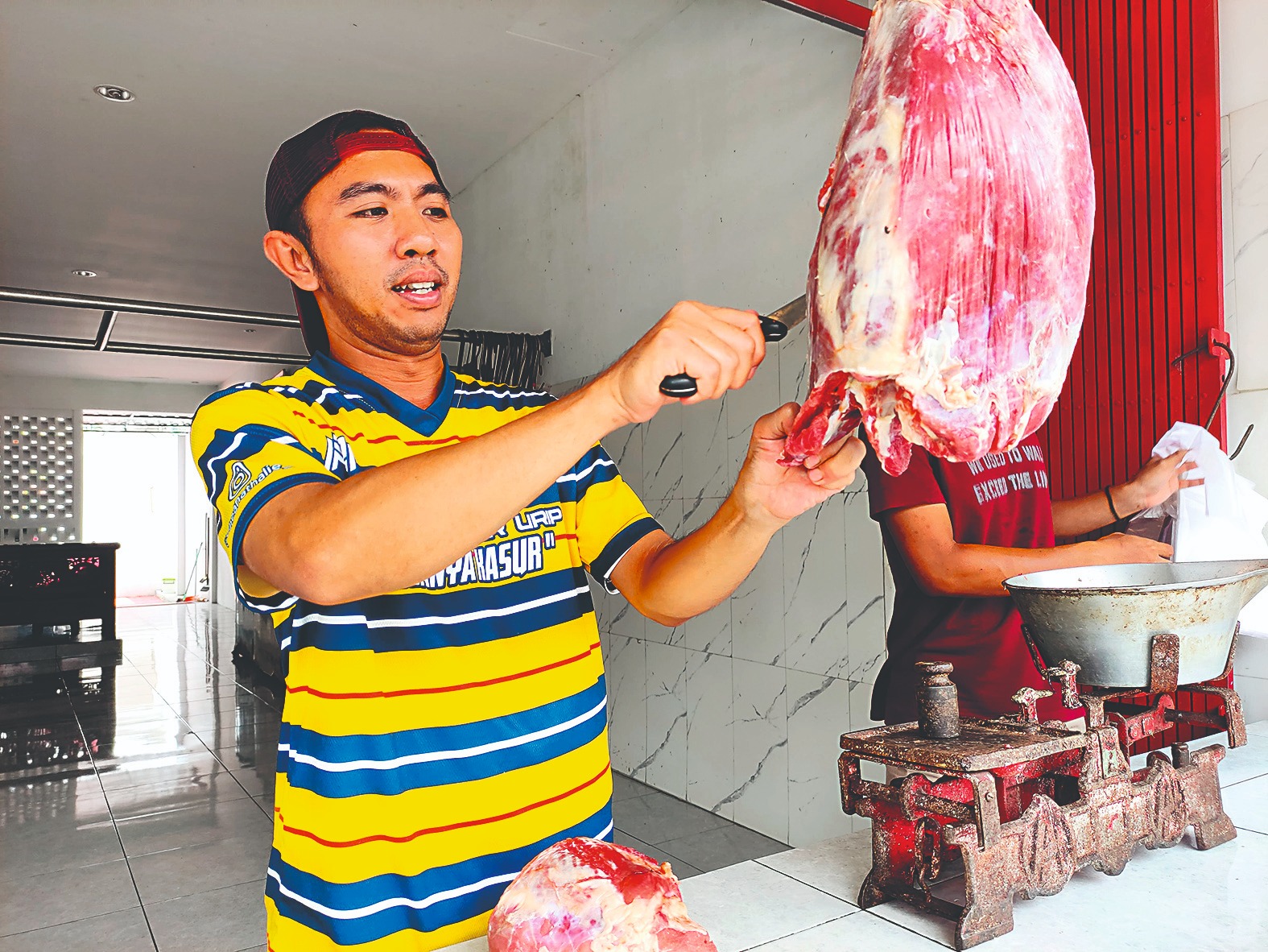 Salah seorang penjual daging sapi di  dekat Pasar Ngemplak sedang melayani pembeli.
