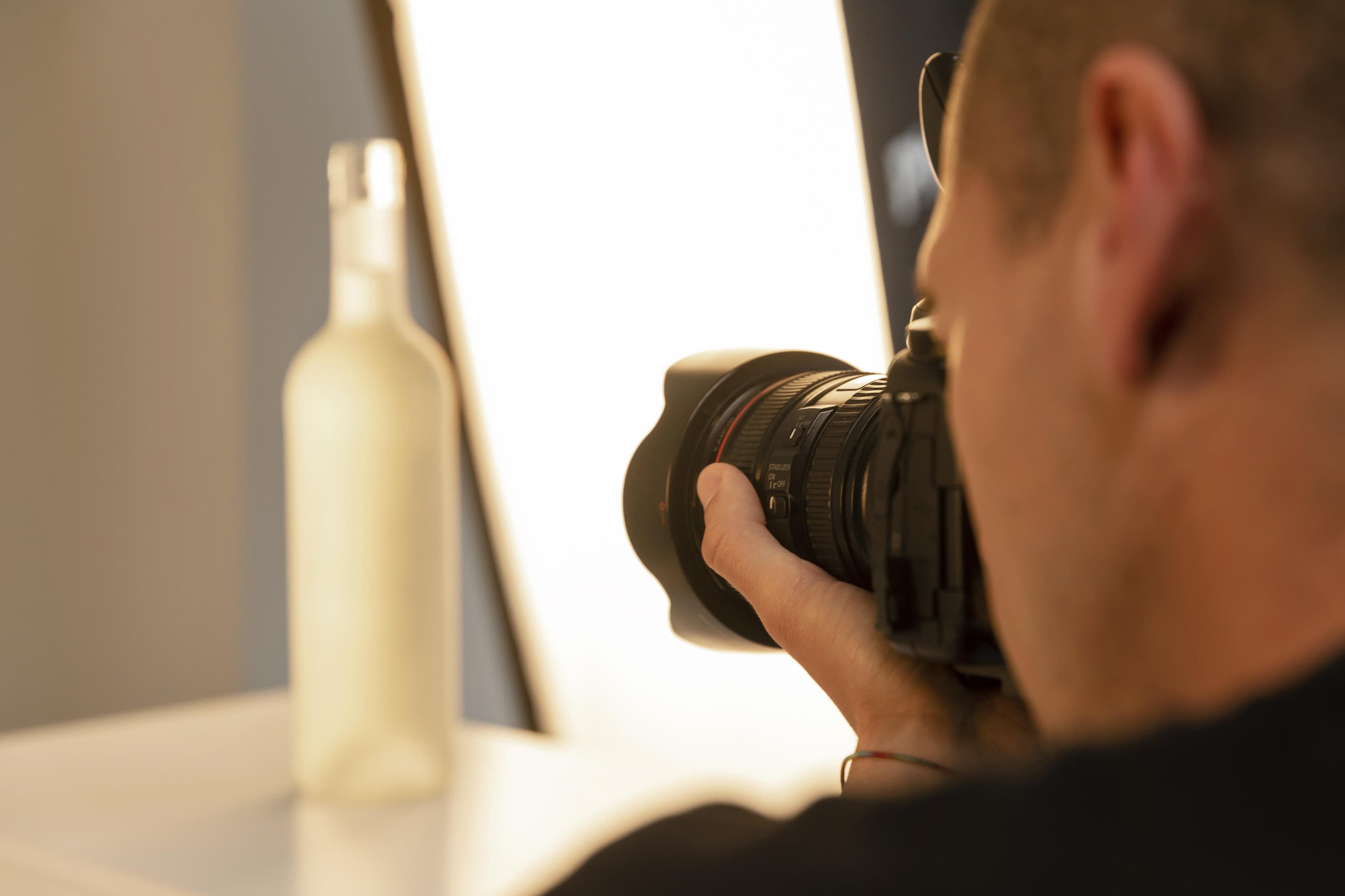 Seorang fotografer sedang memotret botol dengan latar belakang bokeh