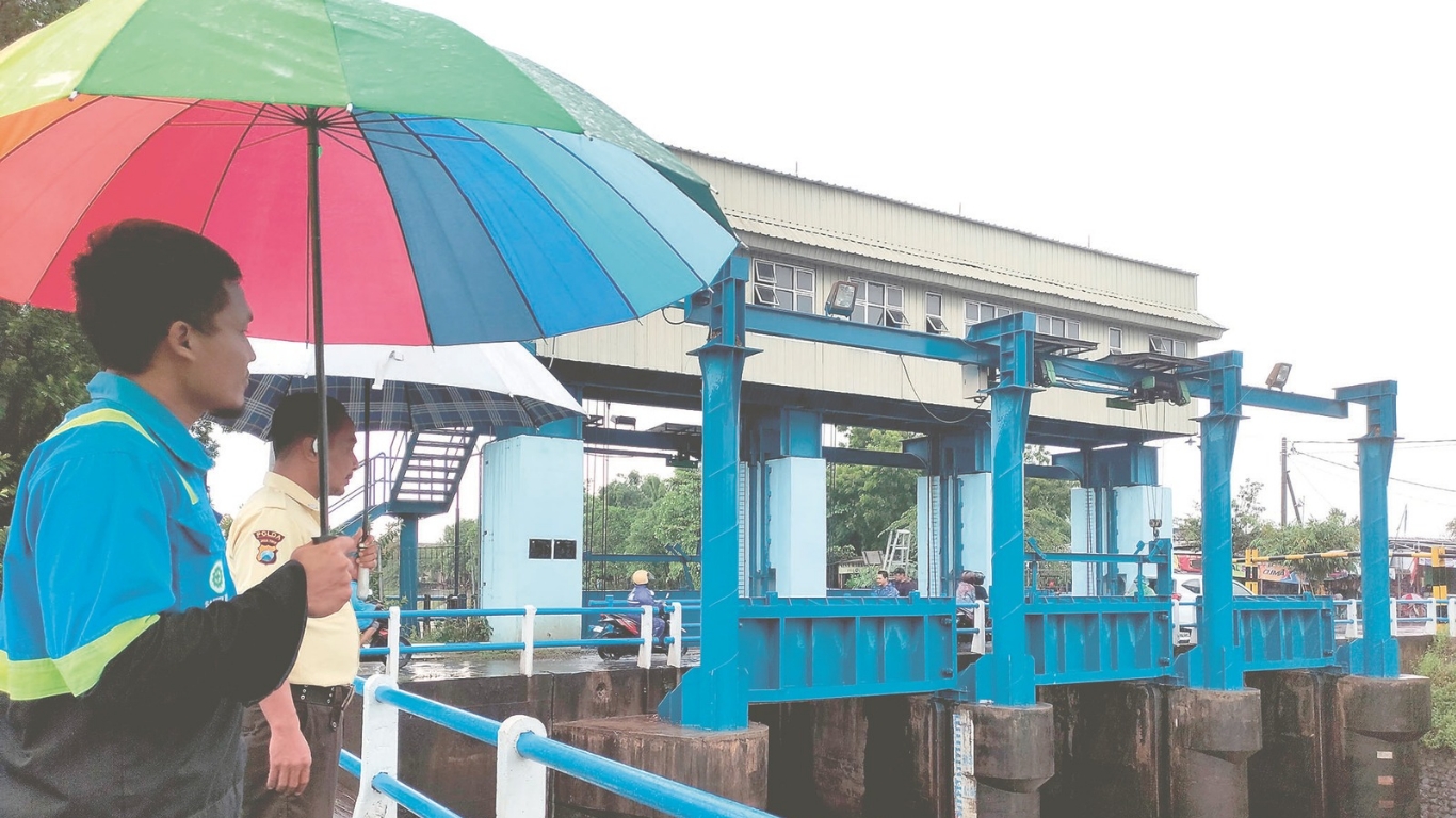 Dua pekerja Dam Majan, Kecamatan Kedungwaru, sedang mengawasi peningkatan volume air.(SANDY YUWANA/RADAR TULUNGAGUNG)