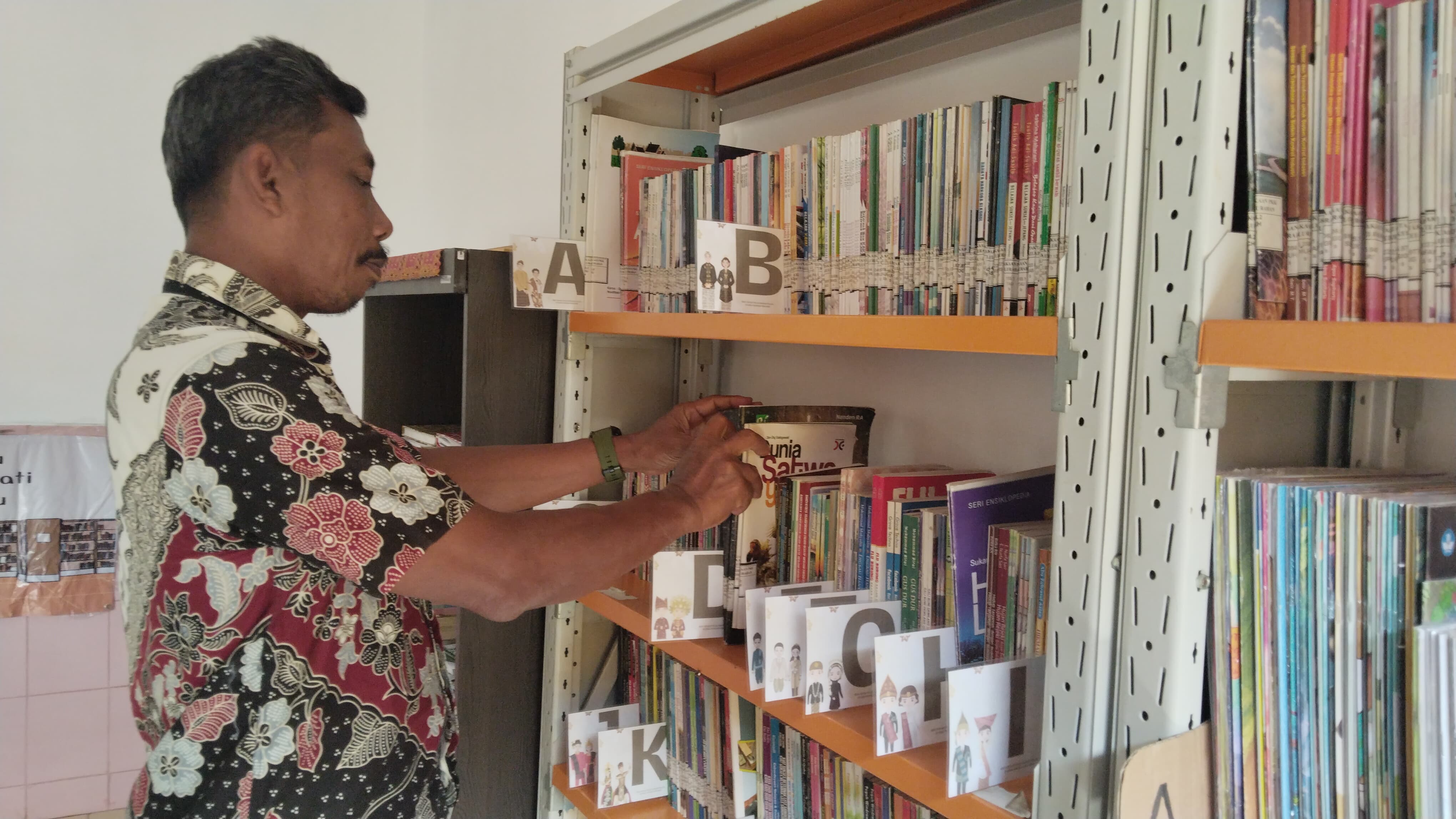 Sekdes Pandean Supriadi menunjukkan koleksi buku di perpusdes. (WANDA AK/RADAR TRENGGALEK)