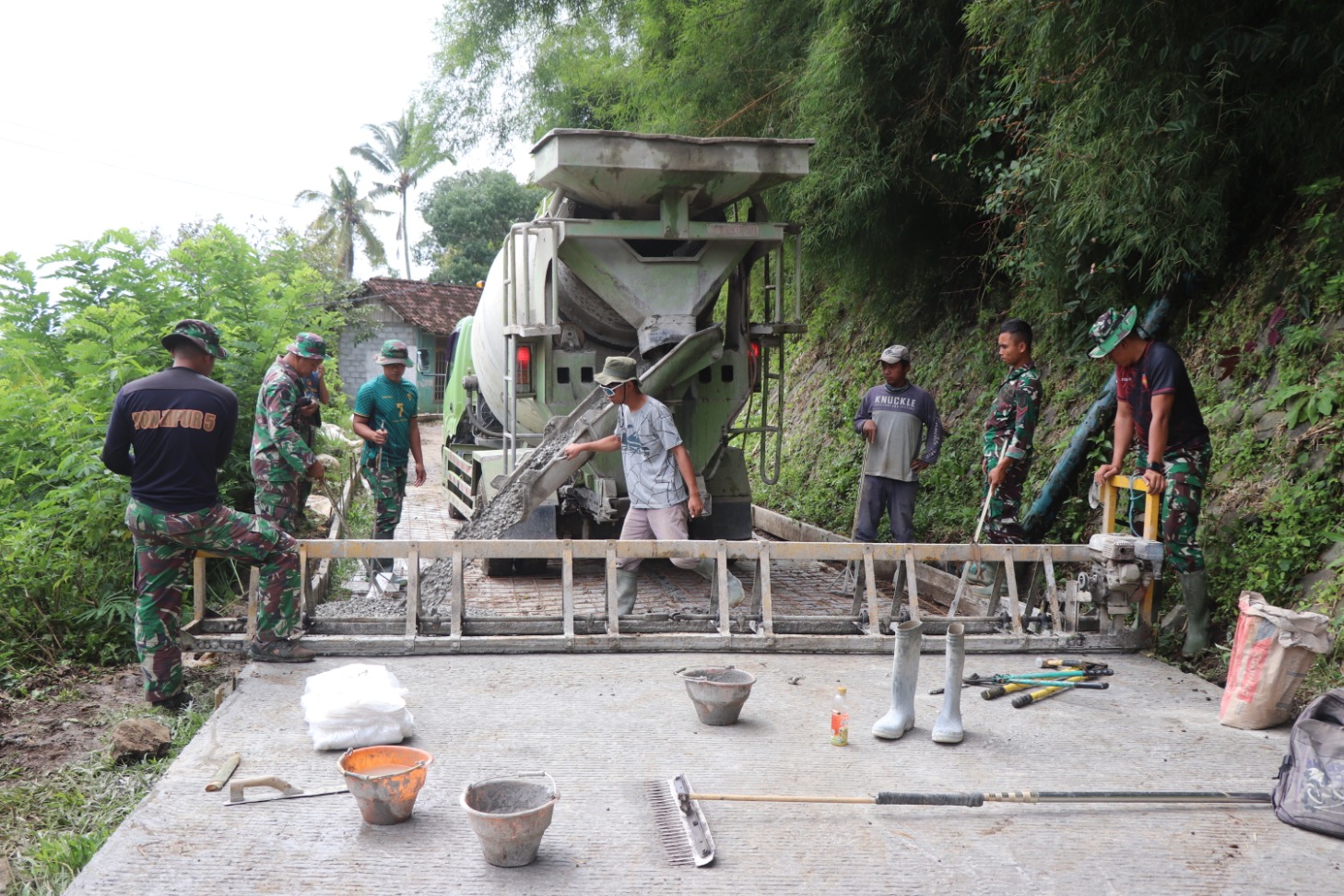 Personel Kodim 0807/Tulungagung dan warga Desa Nglurup, Kecamatan Sendang membangun rabat jalan. (YOGA DD/RADAR TULUNGAGUNG)