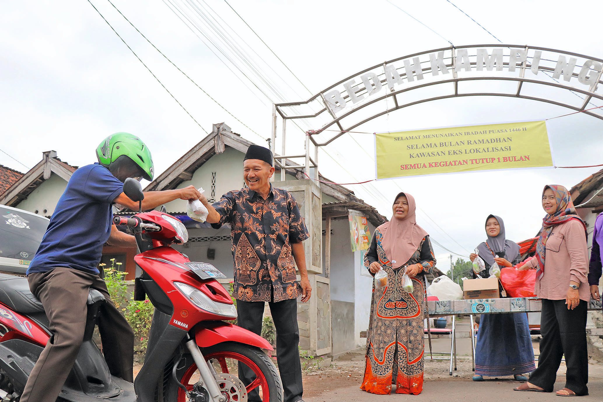 Kepala Desa Ngujang Siswandi membagikan takjil kepada pengguna jalan yang melintas di dekat eks lokalisasi. (YOGA DD/RADAR TULUNGAGUNG)