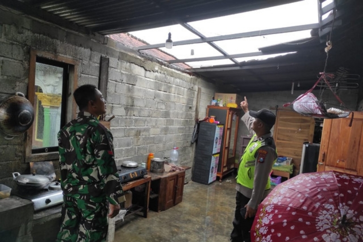 Personel polisi dan TNI menunjukkan atap rumah warga Desa Wates, Kecamatan Campurdarat yang tersapu angin pada Sabtu (8/3) sore. (HUMAS POLRES TULUNGAGUNG)