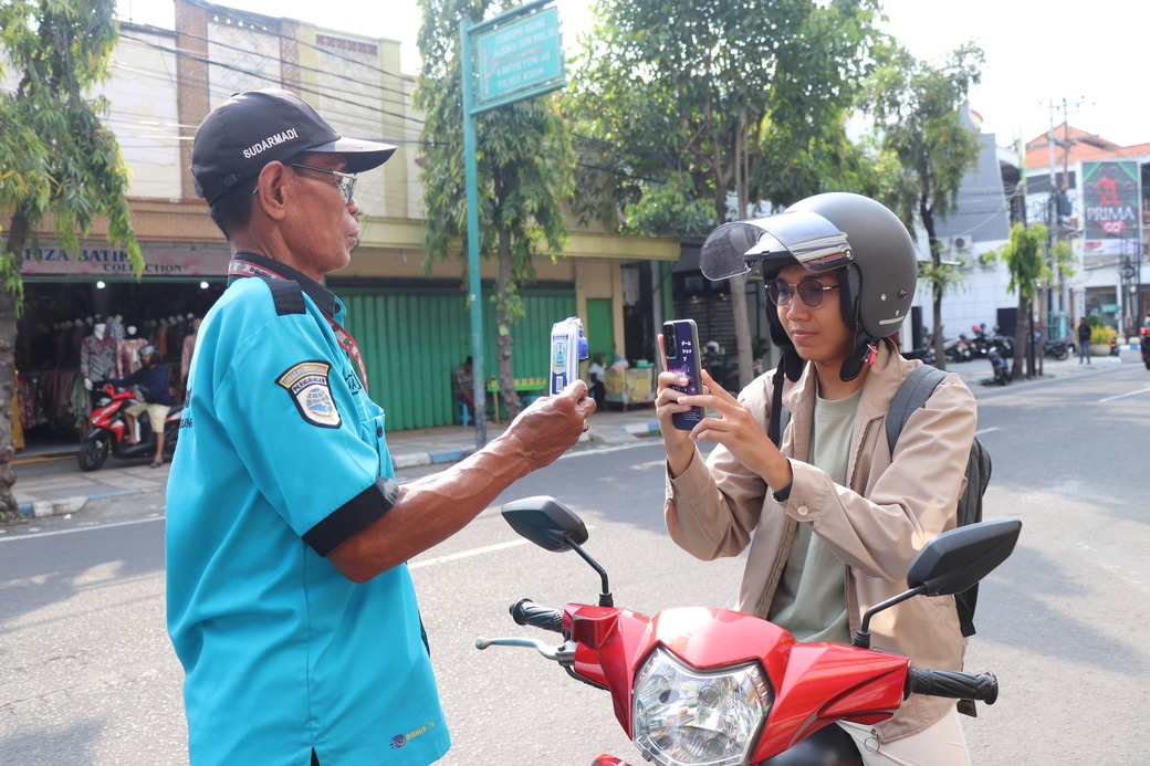 Pelanggan membayar parkir secara secara nontunai ke petugas di Jalan Pangeran Diponegoro.