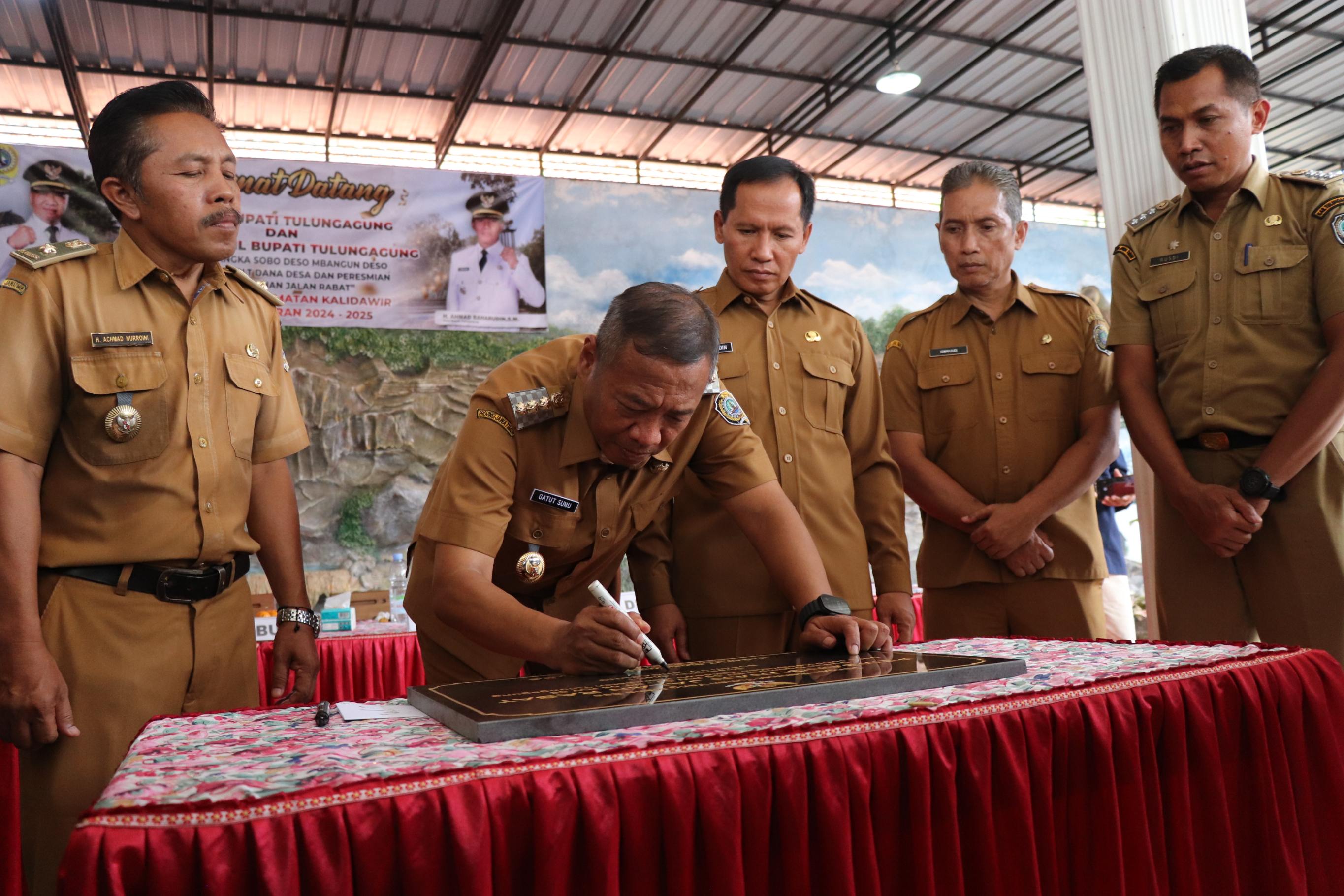Bupati Tulungagung Gatut sunu wibowo  menandatangani prasasti peresmian jalan rabat beton didampingi wabup, camat Kalidawir, dan Kades Joho. (YOGA DD/RADAR TULUNGAGUNG)