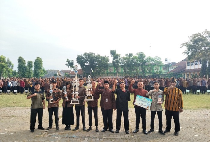 Kepala SMKN 3 Boyolangu berfoto bersama murid di lapangan sekolah serta mengangkat Piala Juara 2 Kategori Bina dan Pasukan Terbaik 3 Tingkat Provinsi Jawa Timur.