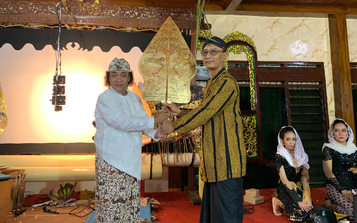 Kepala Desa Plandaan, Kecamatan Kedungwaru, Tulunggung, Fauzi Surahmad sedang melakukan prosesi penyerahan wayang kulit kepada Dalang Ki Budi Plandang pada puncak acara bersih desa, Jumat (16/5/2025).