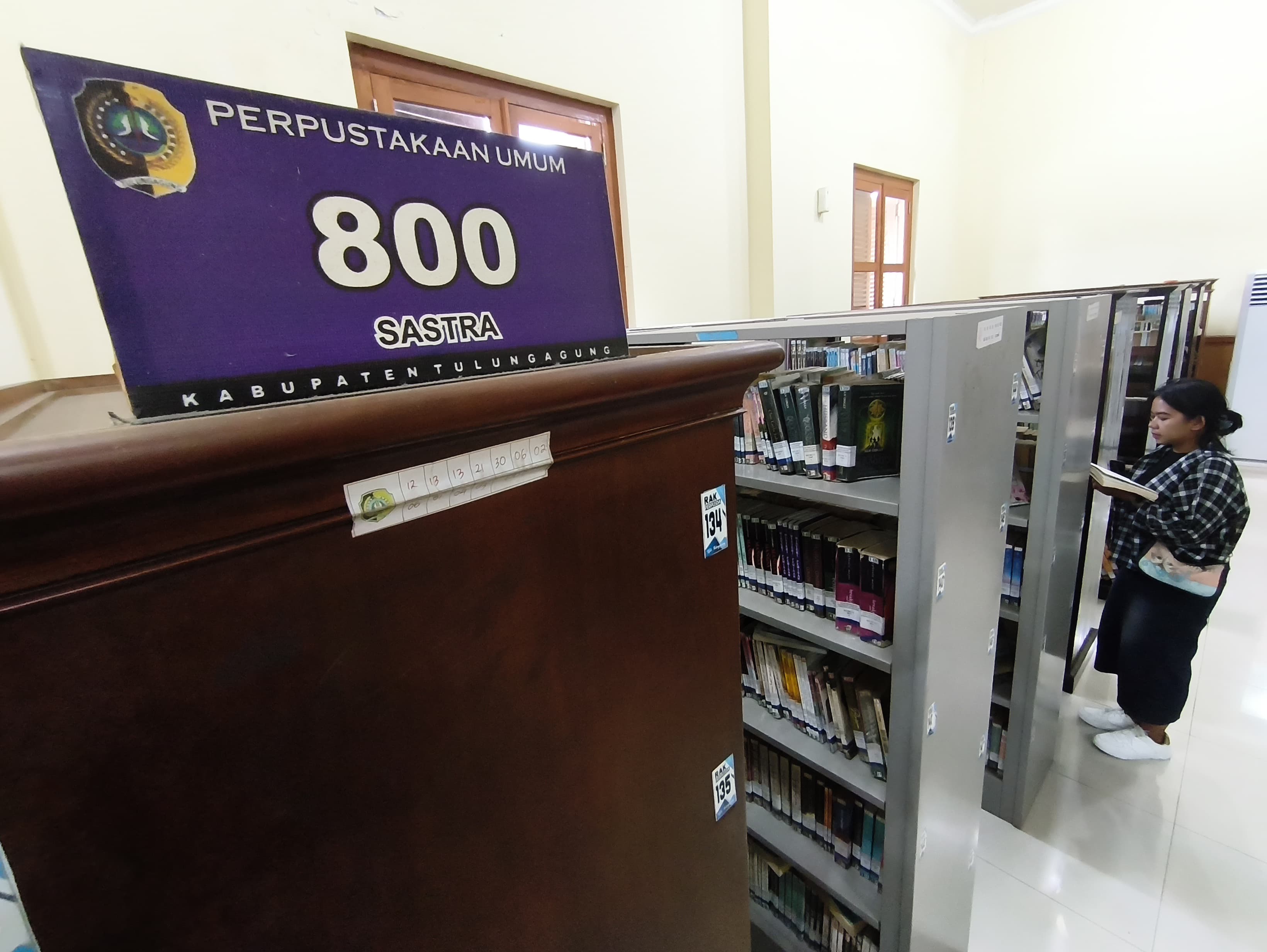 Pengunjung perpustakaan daerah membaca salah satu koleksi buku.