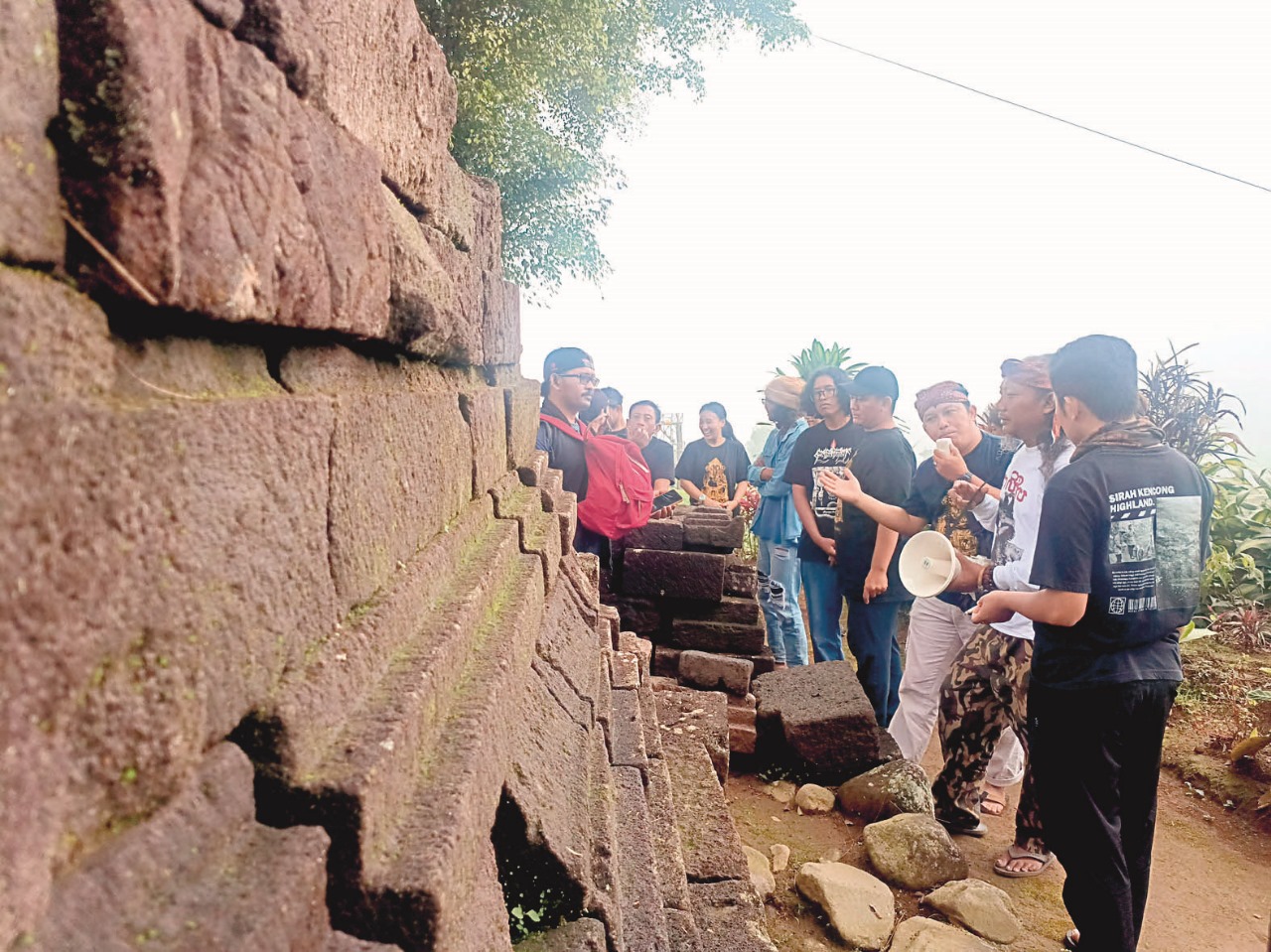 Peserta kopdar pegiat aksara Kawi saat mengamati  bebatuan di area Candi Sirah Kencong, Blitar, pada Minggu (6/7/2025).
