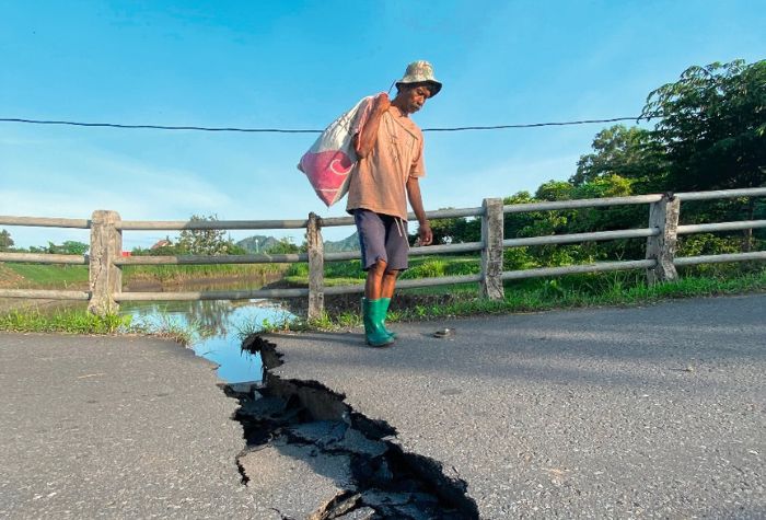 Seorang pencari rumput melintasi jembatan di Desa Junjung, Kecamatan Sumbergempol, yang patah beberapa waktu lalu.(DR PERDANA/RADAR TULUNGAGUNG)