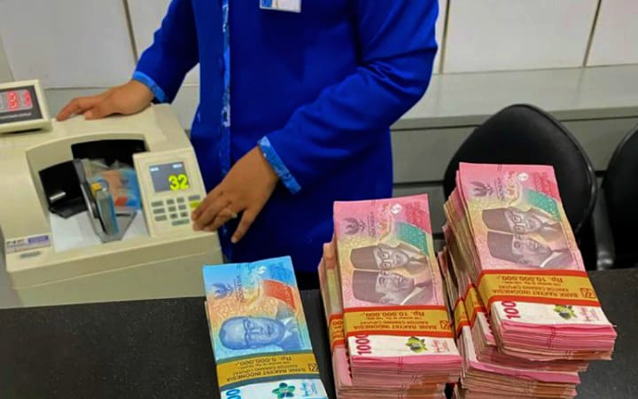 Ilustrasi tumpukan uang yang sedang dihitung teller salah satu bank.
