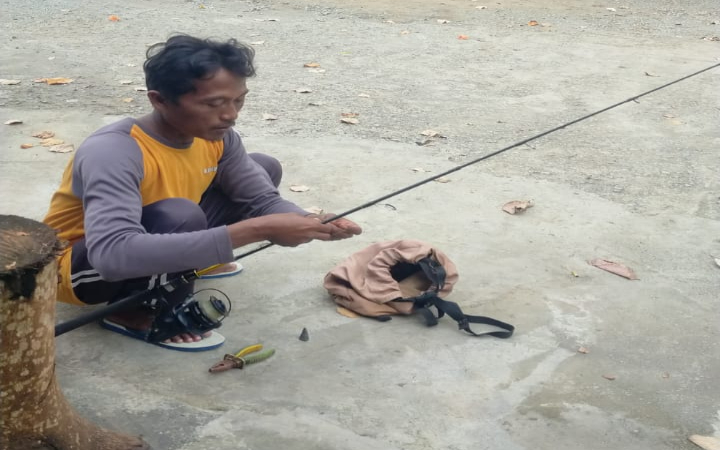 Misdianto menyiapkan peralatan pancing sederhana di sela waktu sebelum mulai kembali melaut. (MISDIANTO UNTUK RADAR TULUNGAGUNG)  &nbsp;