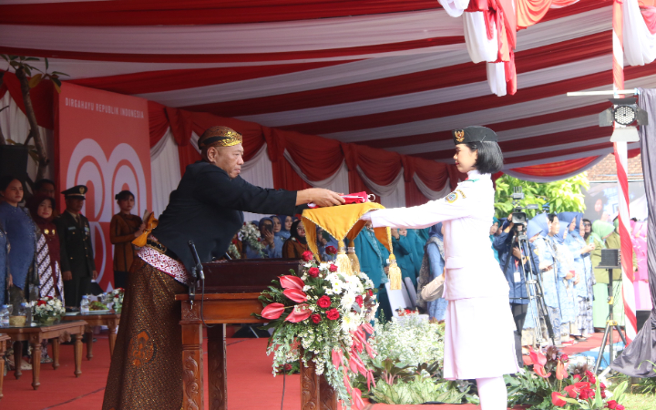 Bupati Tulungagung Gatut Sunu Wibowo memberikan bendera Merah Putih ke paskibra, dalam Upacara HUT ke-80 RI, Minggu (17/8/2025).