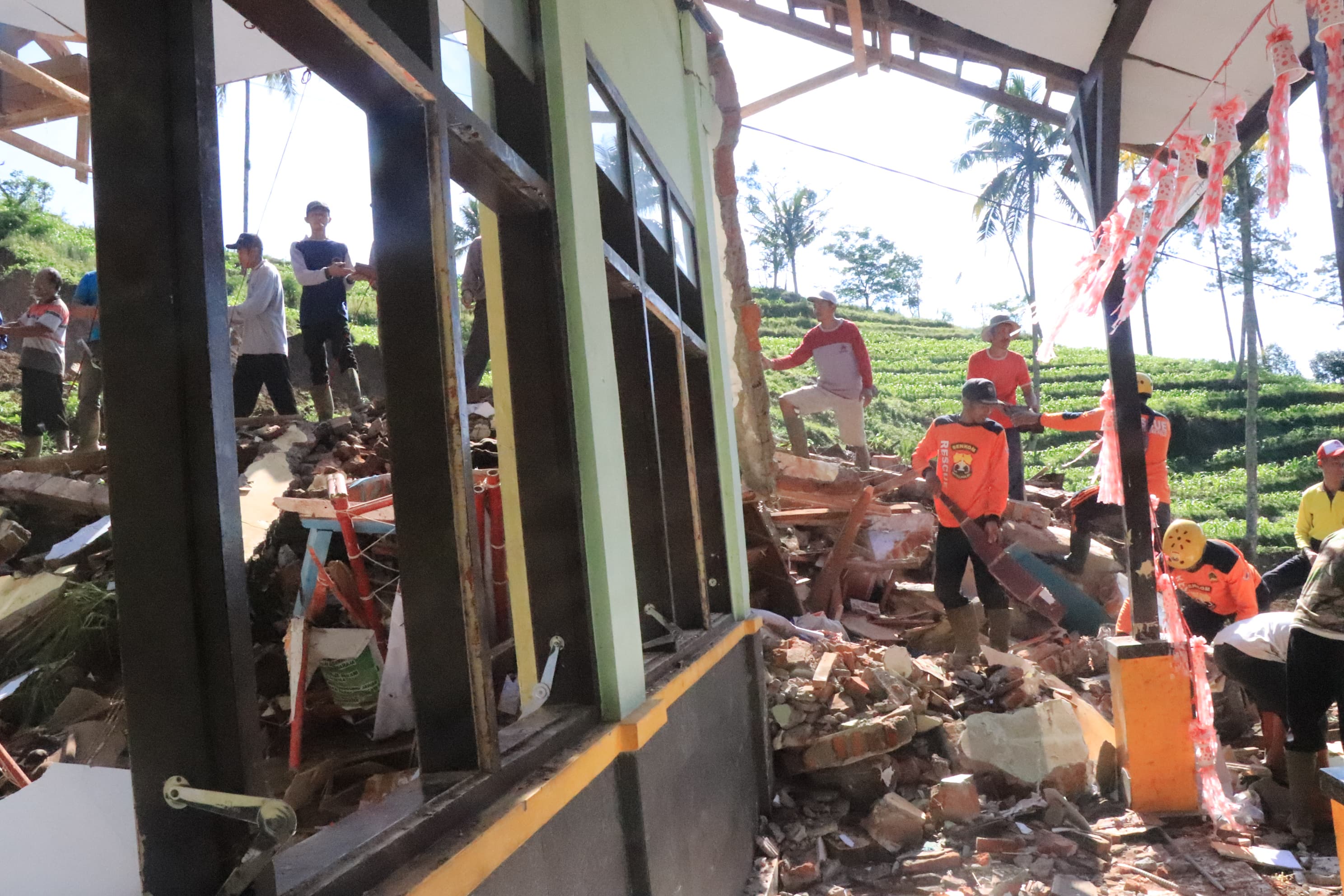 Warga bekerja bakti membersihkan sisa material longsor di SDN 2 Kradinan. (SANDY YUWANA/RADAR TULUNGAGUNG)