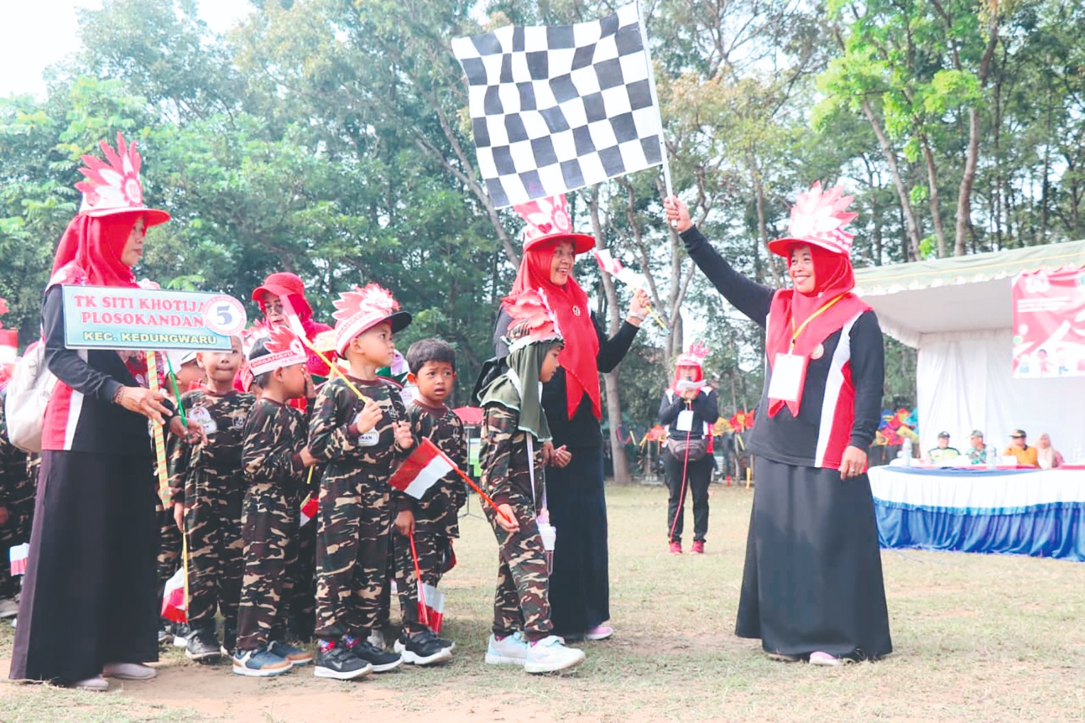 Ketua IGTKI Kedungwaru Nikmaturrohmah mengibarkan bendera start tanda dimulainya jalan sehat. (SANDY YUWANA/RADAR TULUNGAGUNG)