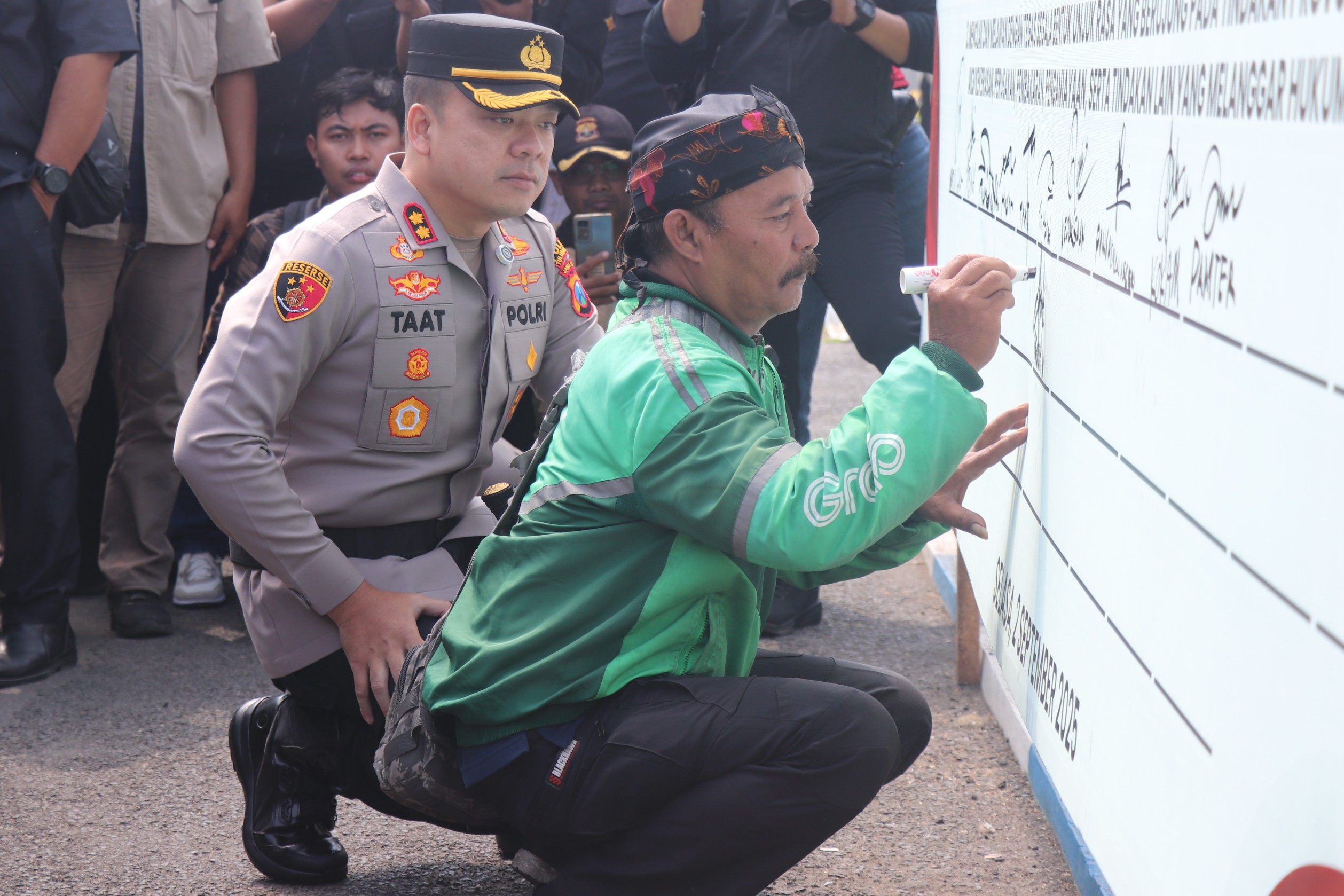 Seorang driver ojol menandatangi pakta integritas untuk menjaga keamanan Tulungagung. (SANDY YUWANA/RADAR TULUNGAGUNG)