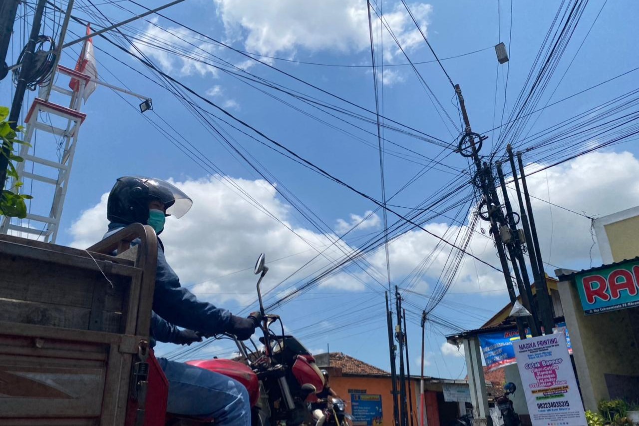 Kabel berbagai ukuran berjuntai di jalan kabupaten di Desa Sobontoro, Kecamatan Boyolangu. (DR PERDANA/RADAR TULUNGAGUNG)