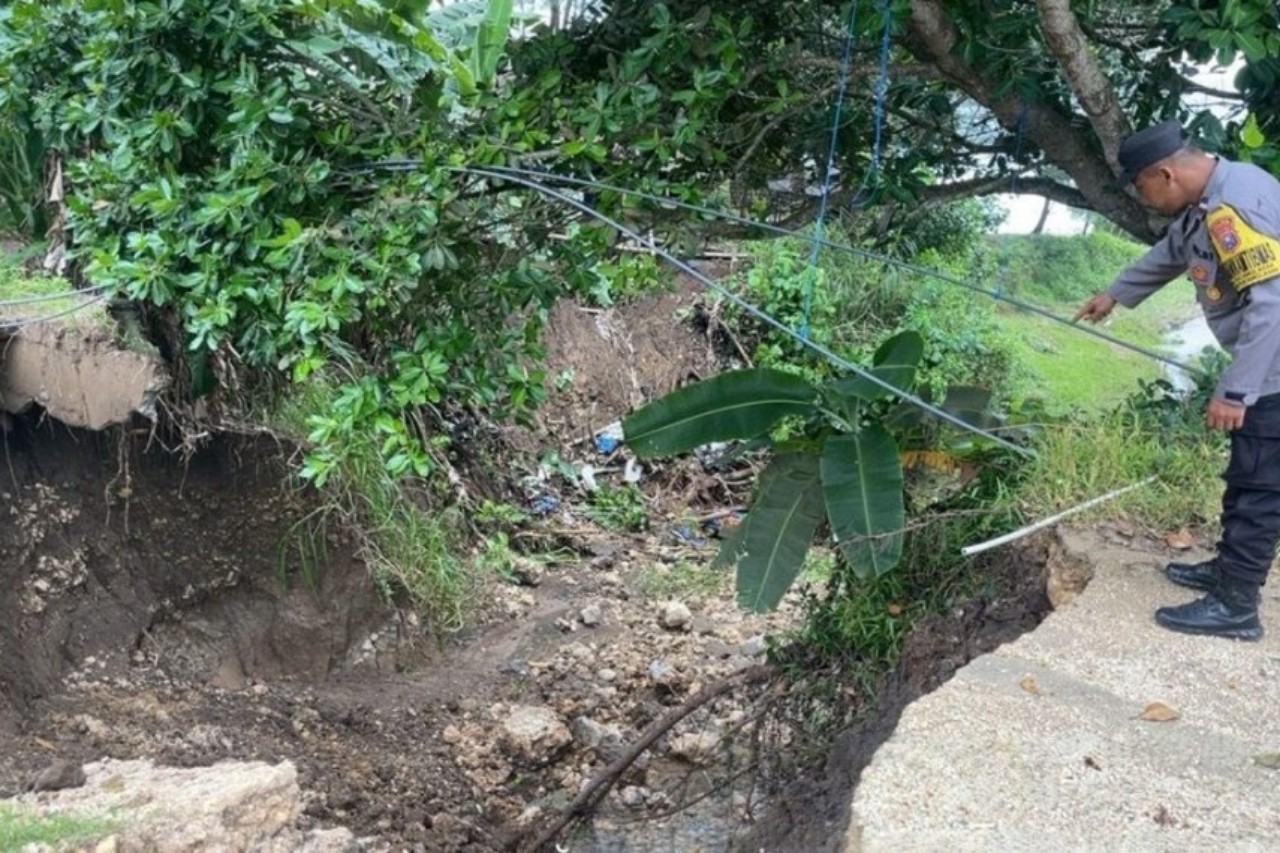 Polisi menunjukkan akses menuju Pantai Ngelinci yang putus akibat longsor. (TRIBRATANEWS)