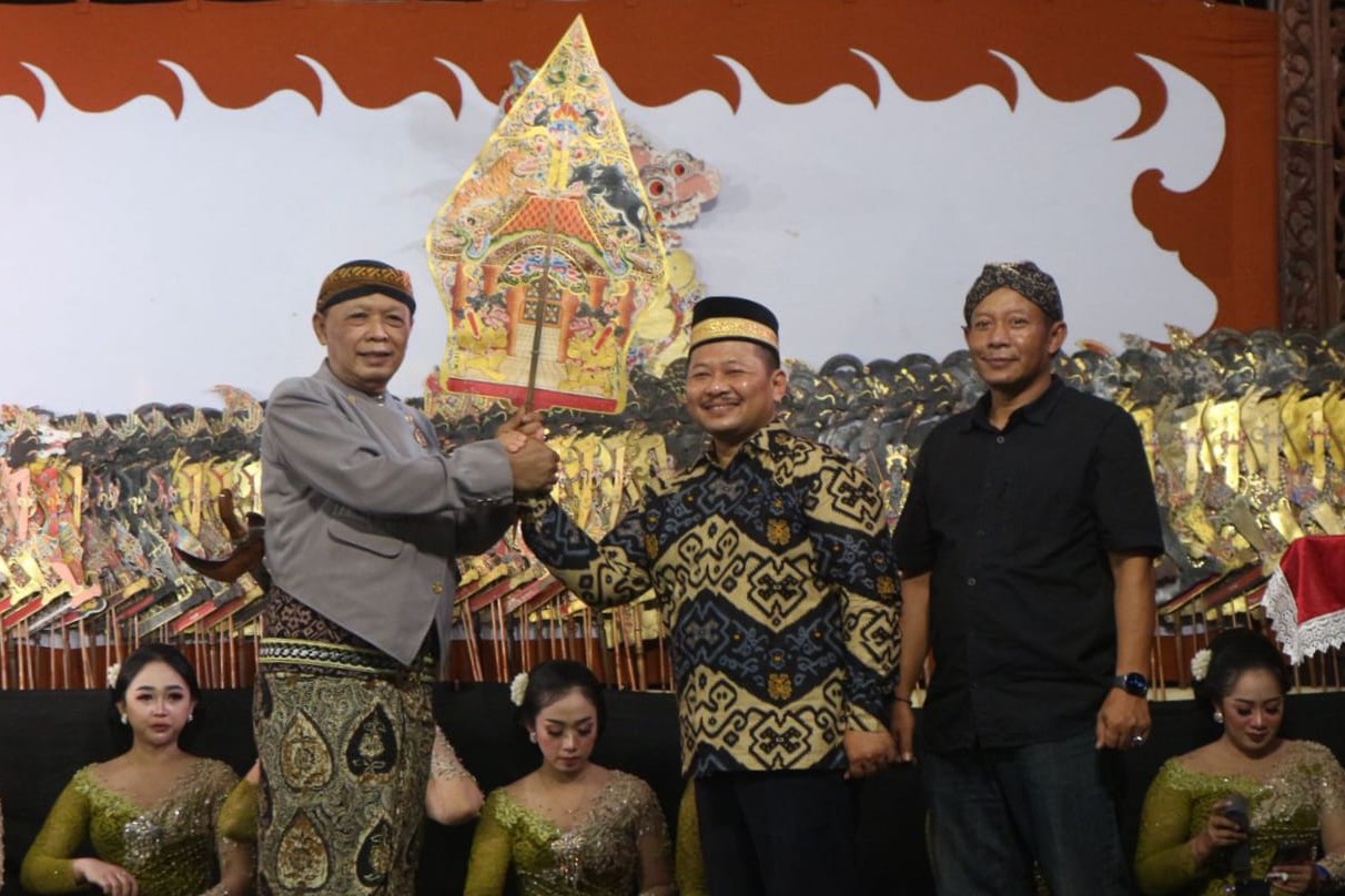 Camat Bandung Chanief Djatmika Nugroho menyerahkan kayon pada Ki Minto Darsono. (RINTO WAHYU/RADAR TULUNGAGUNG)