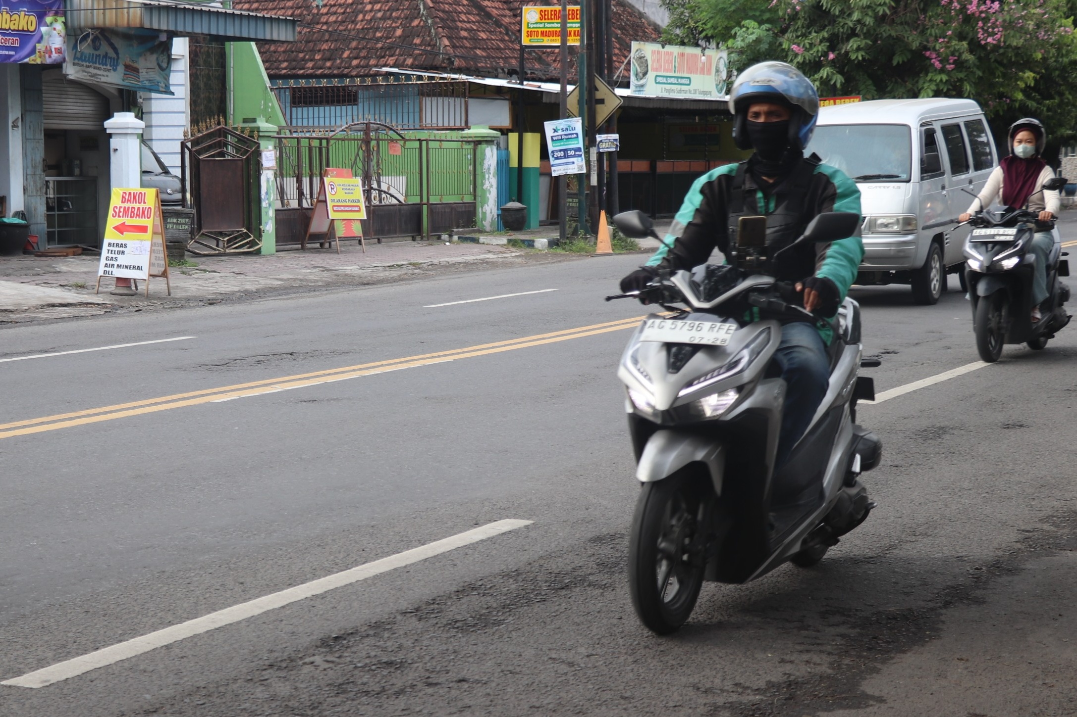 Seorang ojol sepeda motor melaju di jalanan Tulungagung. (ANNIZA MEINA/RADAR TULUNGAGUNG)