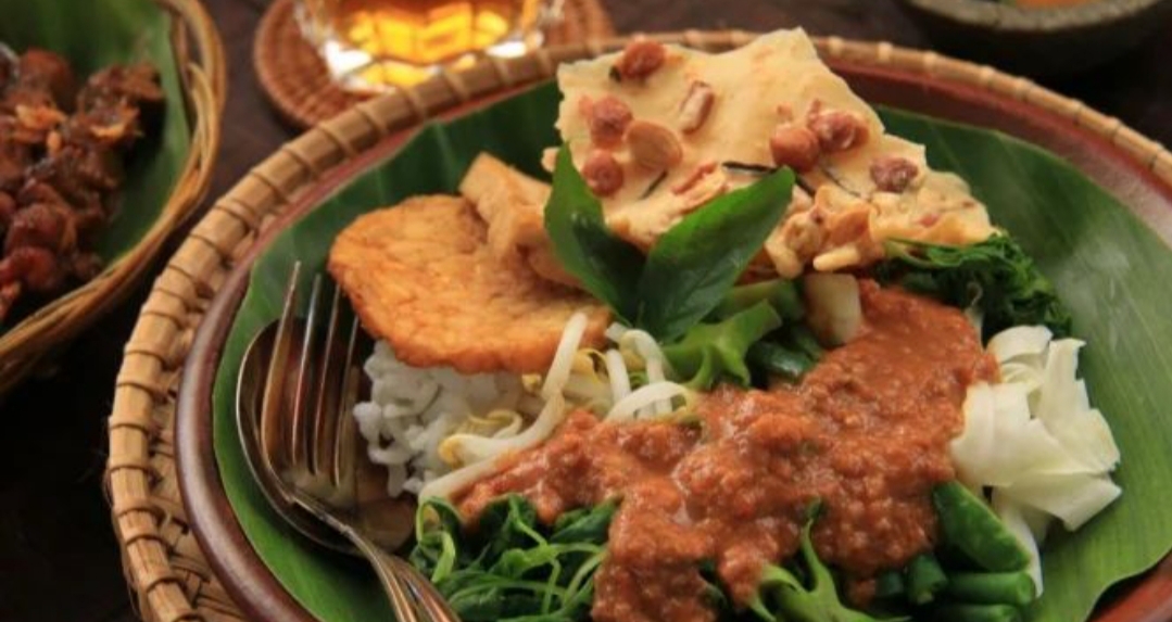 Warung pecel sudah hidup bahkan sebelum matahari benar-benar naik. Daun pisang dibuka perlahan, uap nasi mengepul, sambal kacang diaduk tanpa tergesa