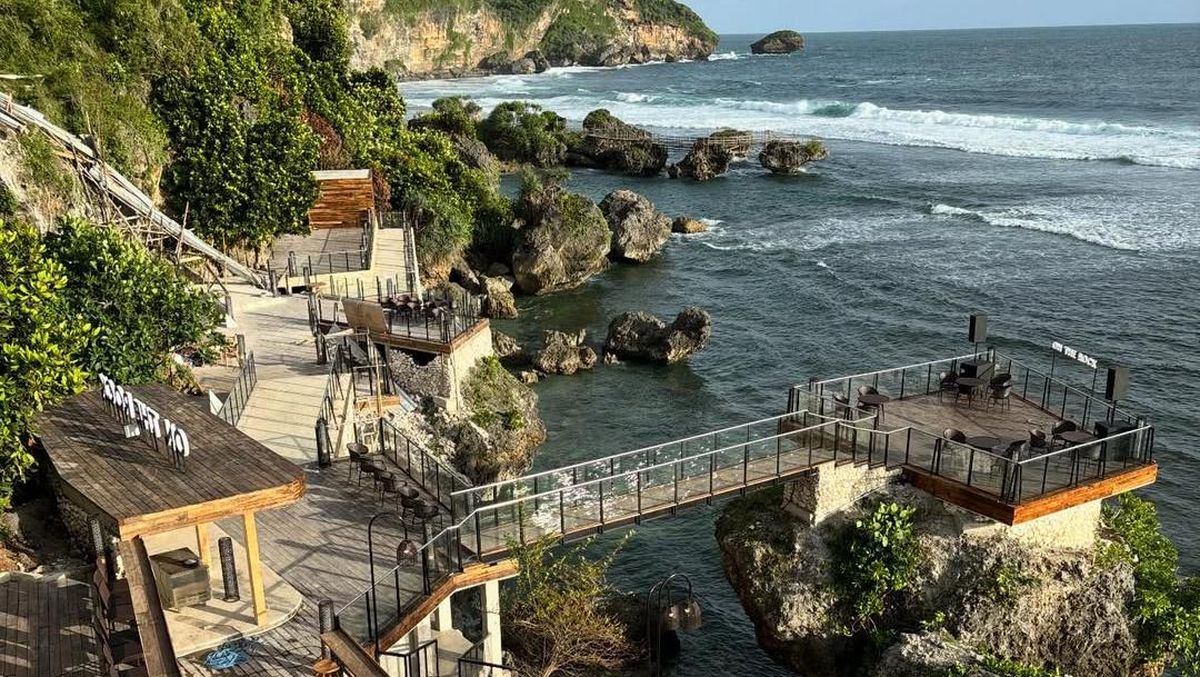 Pemandangan indah On The Rock di Pantai Drini, dengan batu karang, restoran, dan laut biru yang memikat.