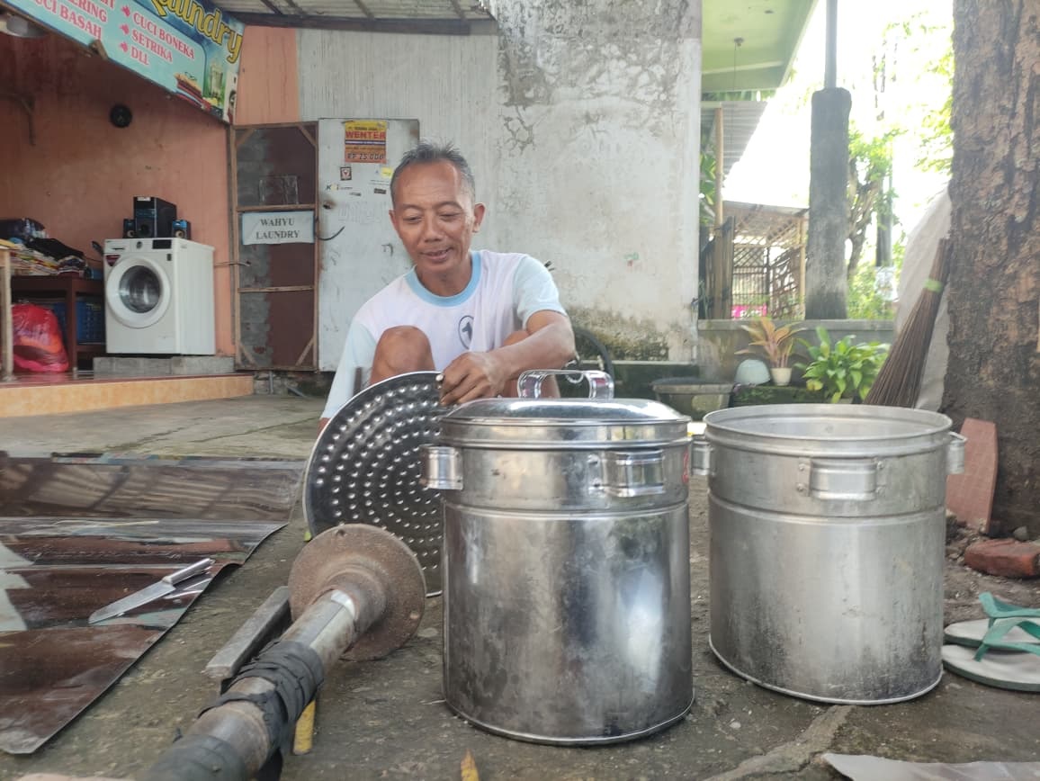 Suwantek saat memperlihatkan panci dan dandang hasil produksinya.(SANDY SRI YUWANA/RADAR TULUNGAGUNG)